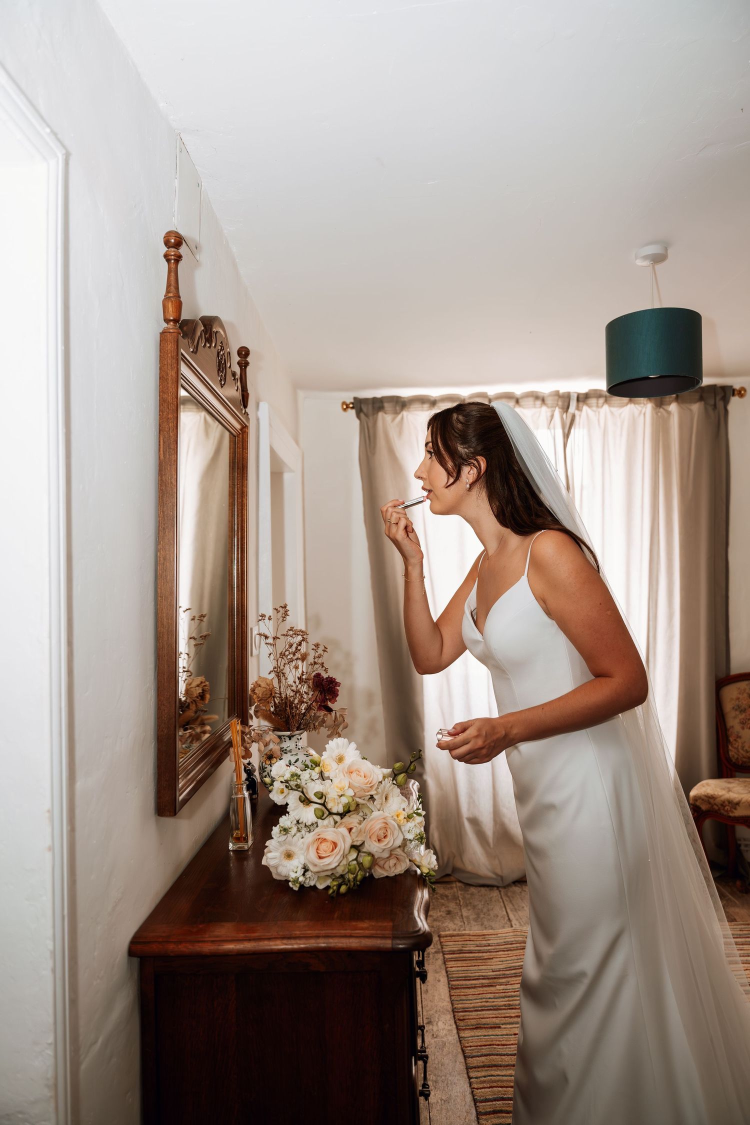 Wedding dress detail shots with antique wooden mirror and floral arrangements.