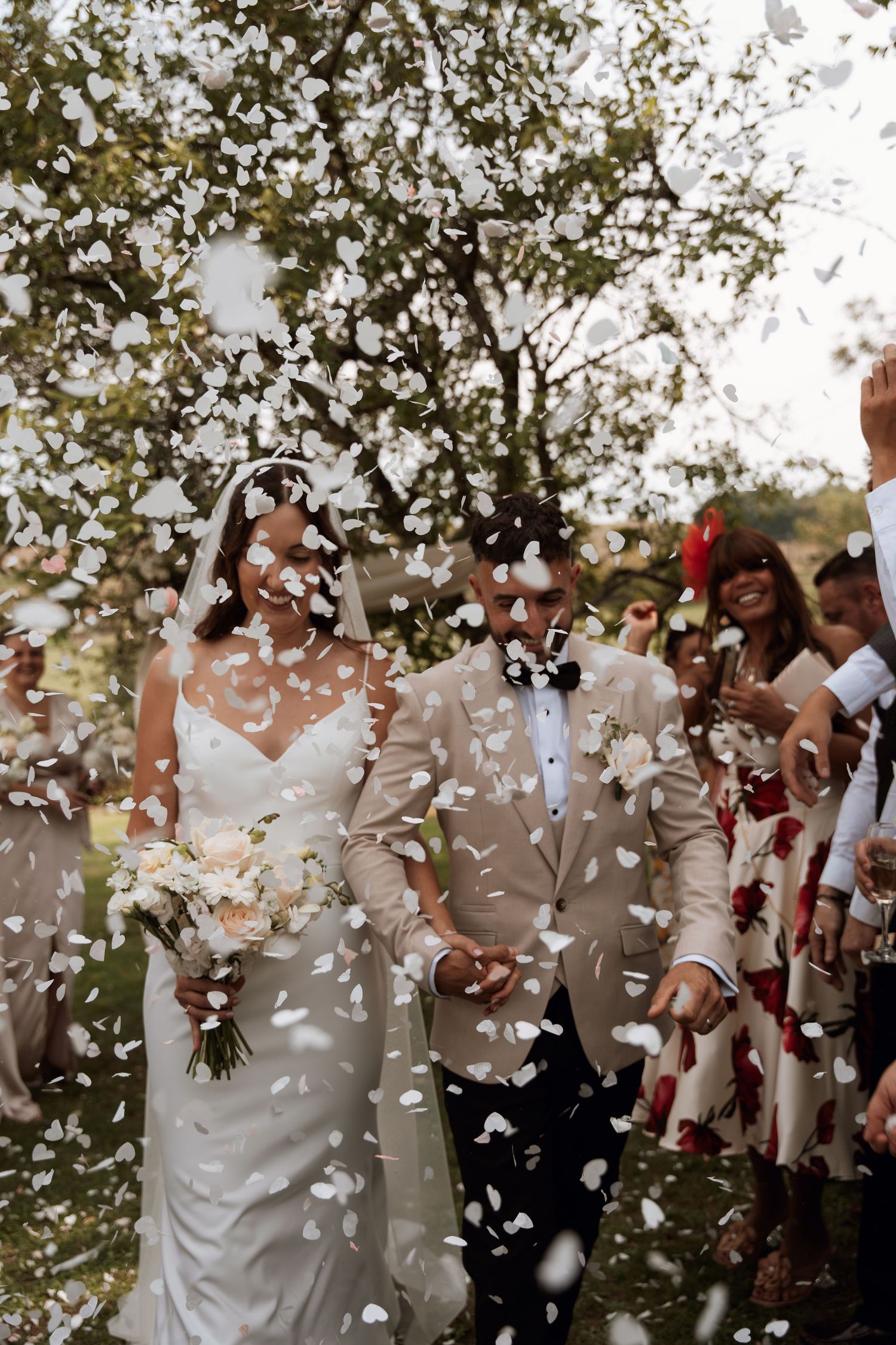 White confetti fills the air during a joyous outdoor celebration.