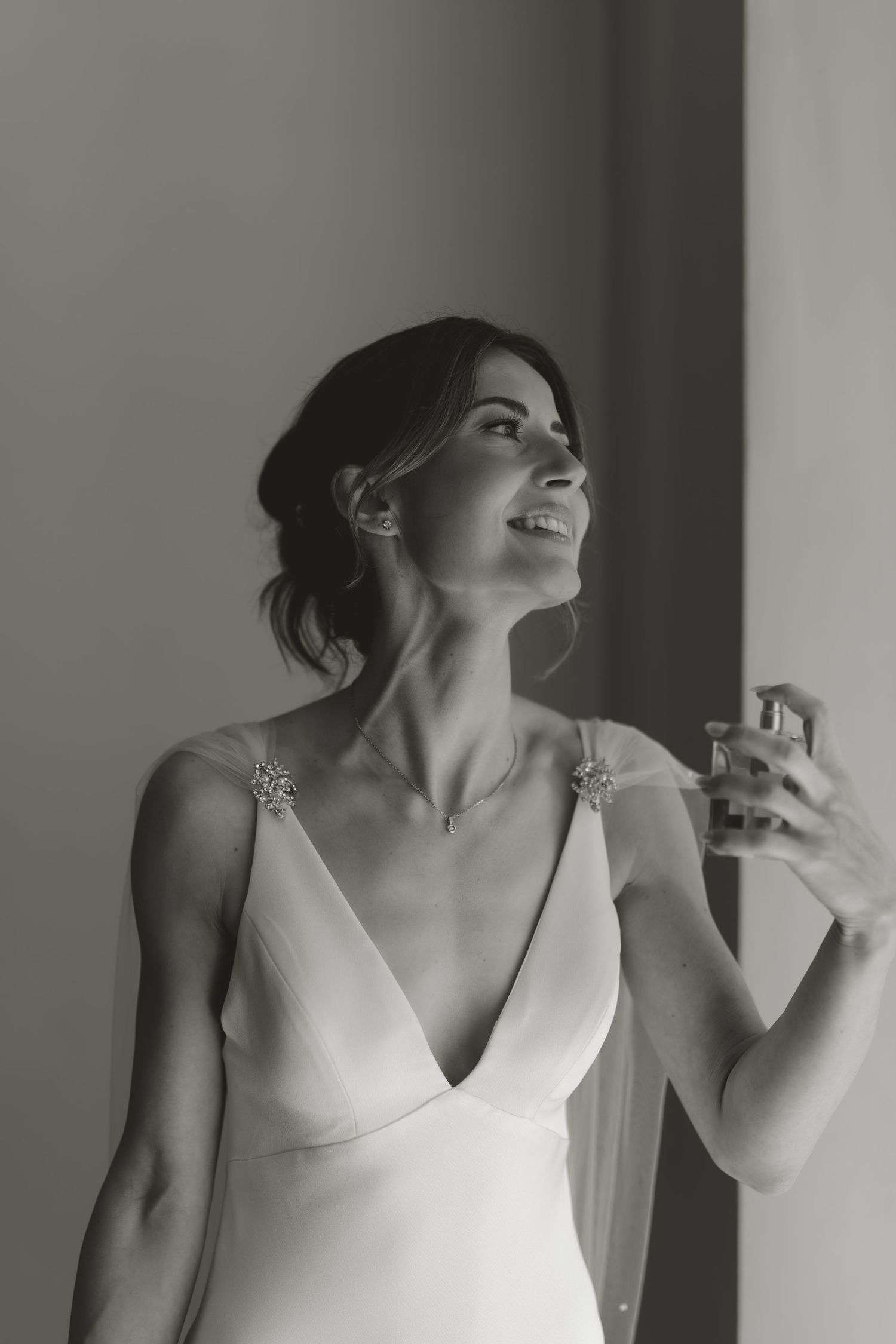 Black and white portraits showing joyful expressions and elegant bridal attire in natural window light.