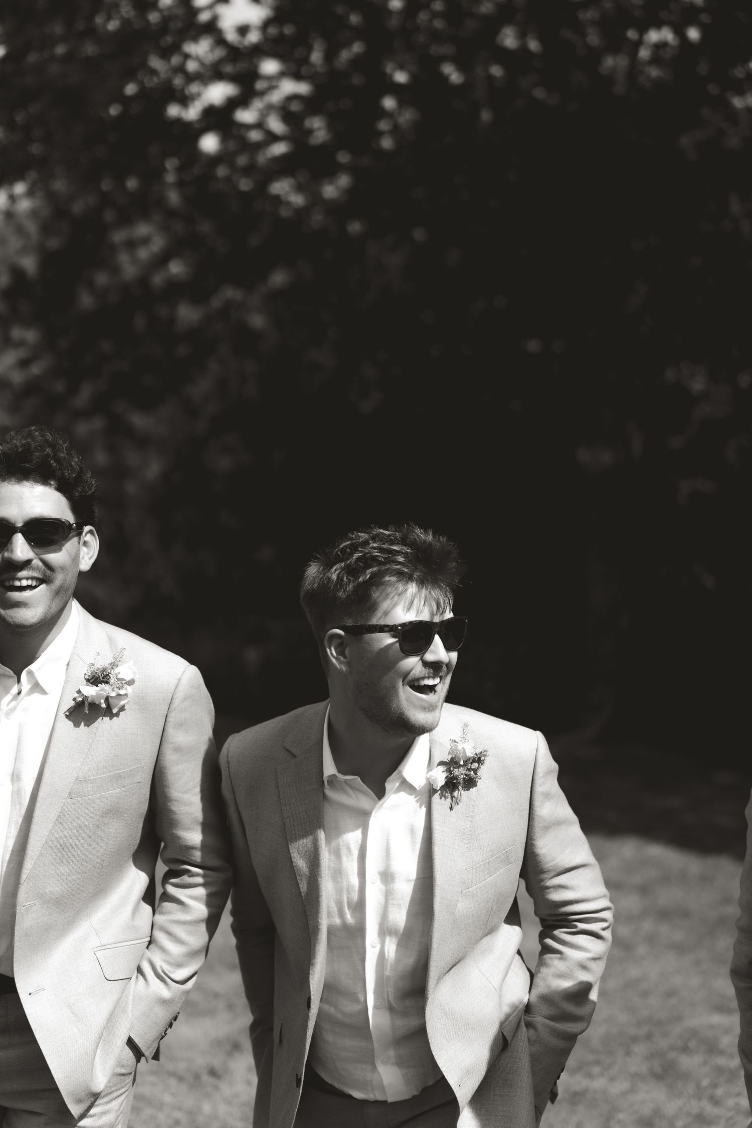 Black and white portrait of groomsmen in light suits and sunglasses.