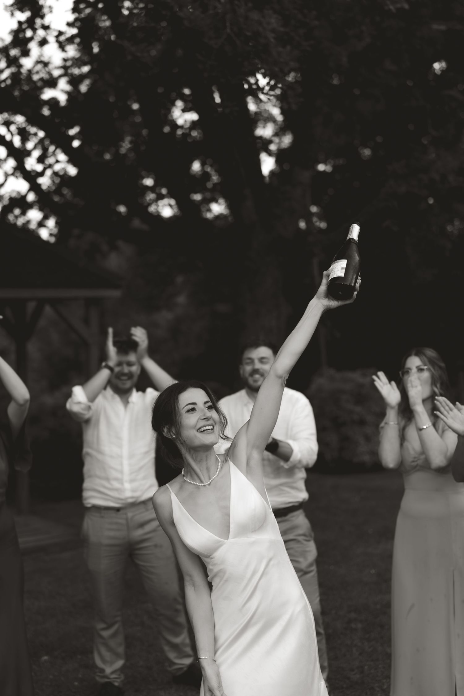 A celebratory moment captured in black and white as people raise their hands in excitement outdoors.
