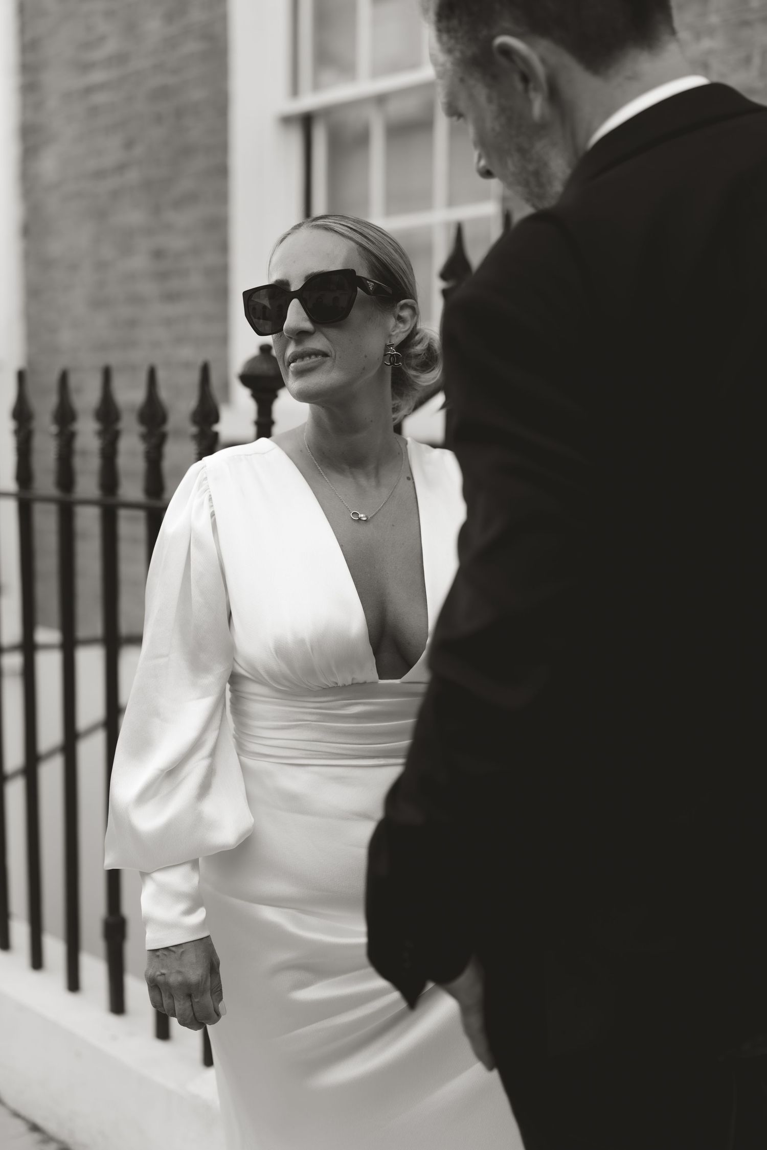 Bride in modern white dress walks with groom in classic tuxedo.
