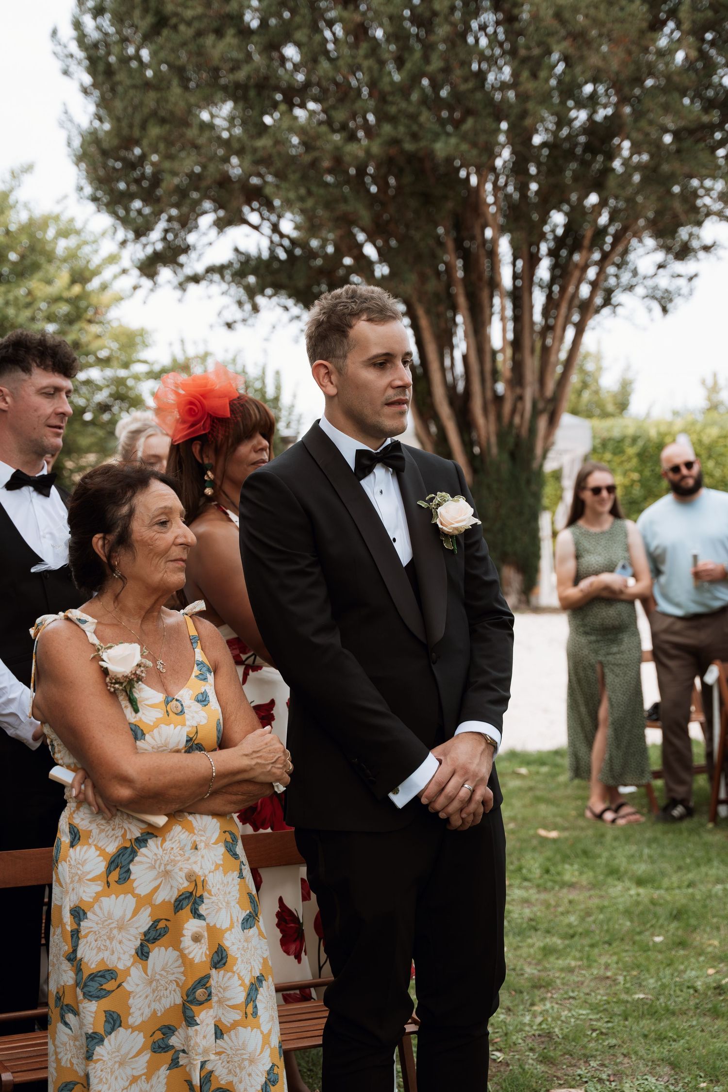 Wedding guests gather on a grassy lawn during an outdoor ceremony.
