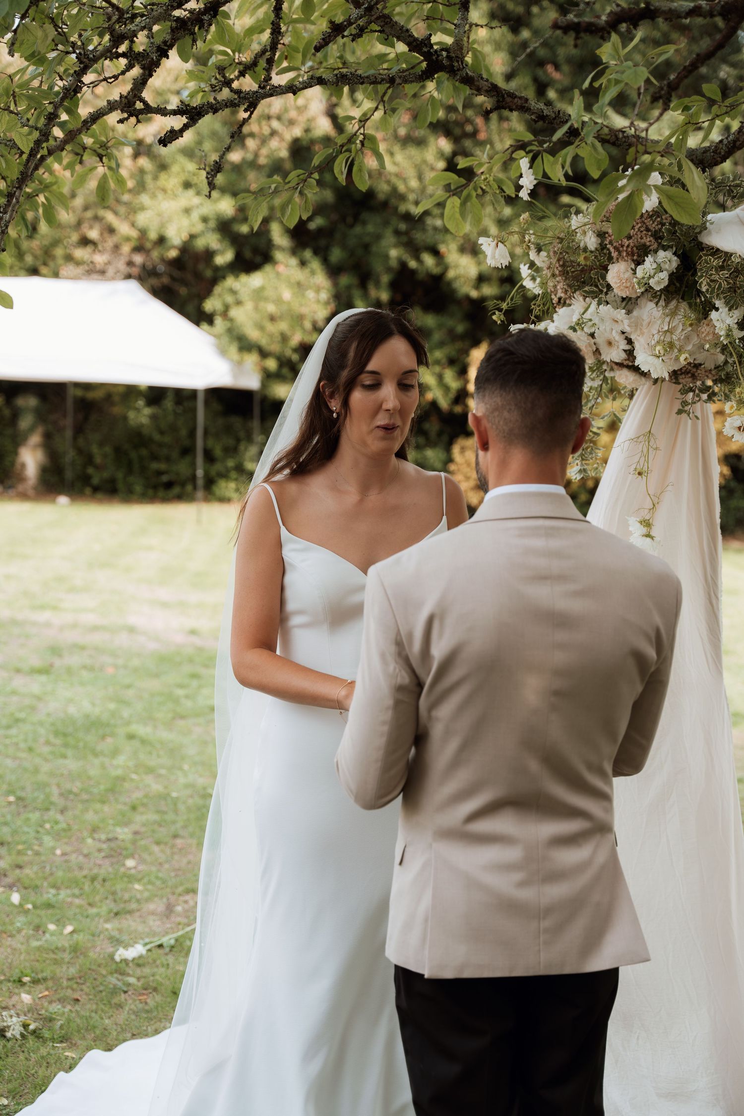 A couple shares an intimate moment under blooming trees during their wedding ceremony.
