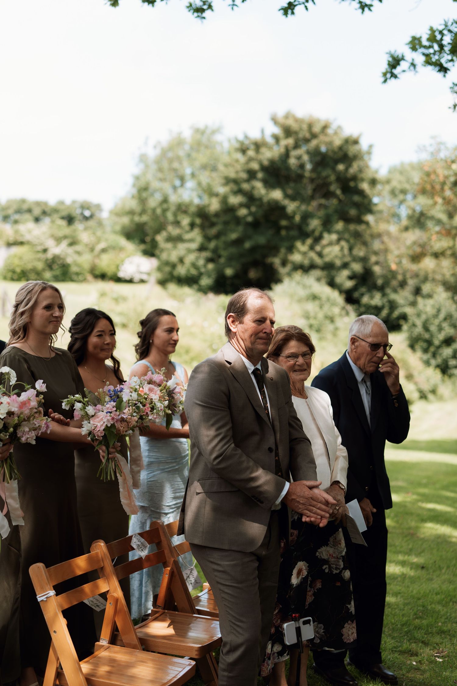 Wedding guests reacting emotionally during an outdoor ceremony.