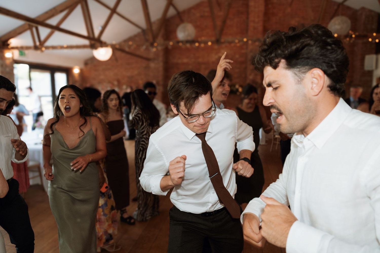Wedding reception dance floor filled with celebration and joy under warm lighting.