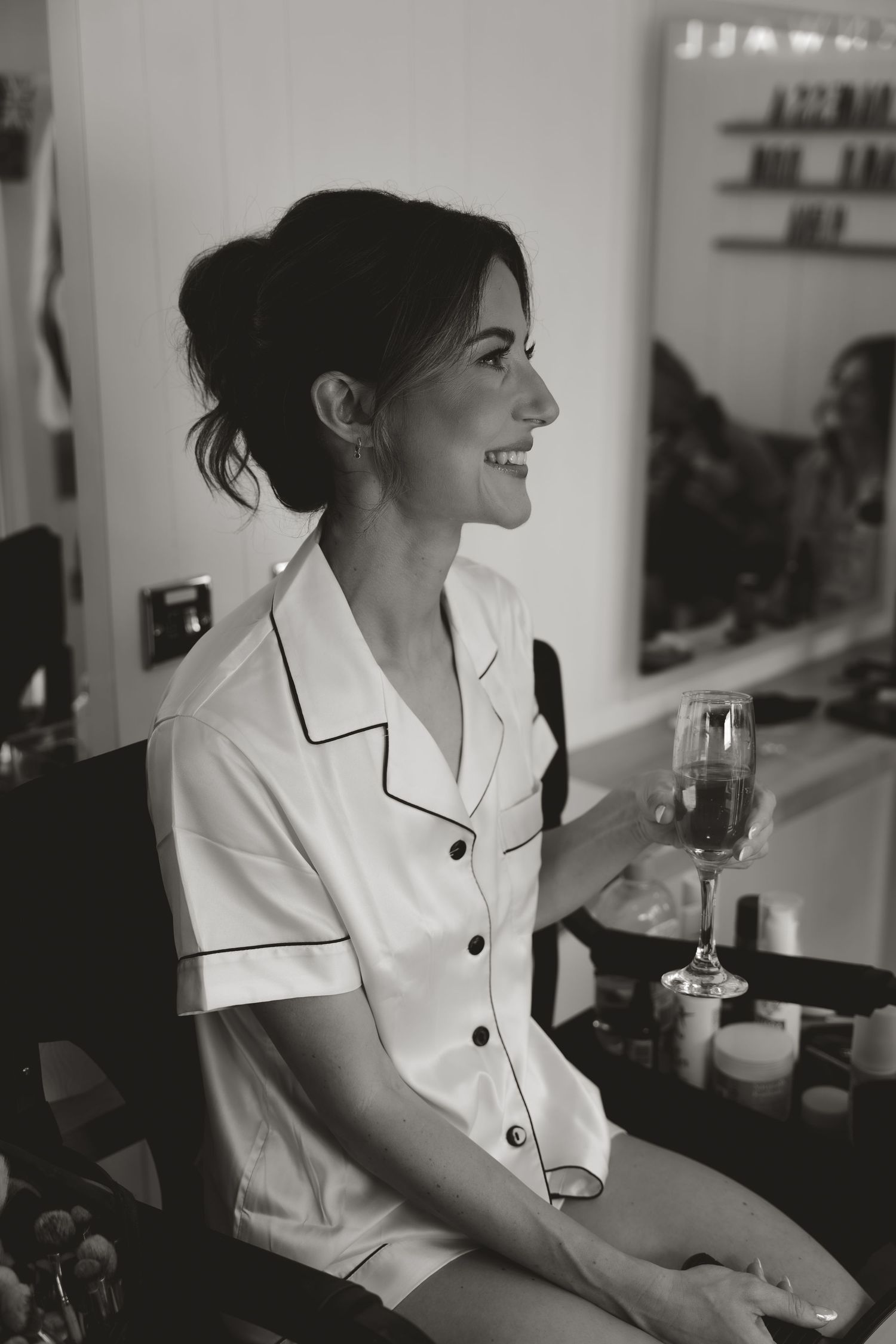 A woman in white pajamas sits relaxed and smiling in a black and white candid photo series.