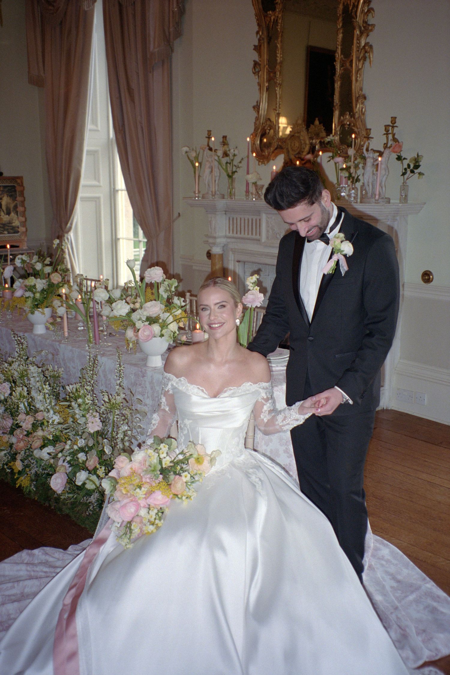 A couple shares a sweet moment together during their wedding reception in an elegant ballroom with floral decorations.