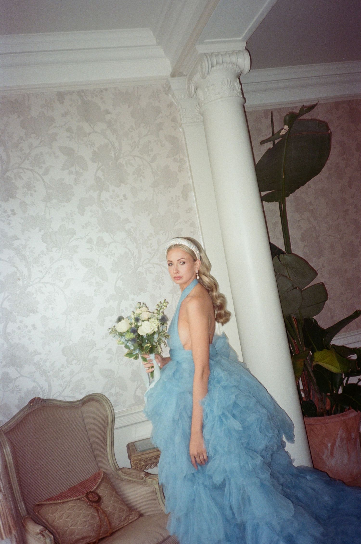 A flowing blue ballgown dress photographed in an elegant interior setting.