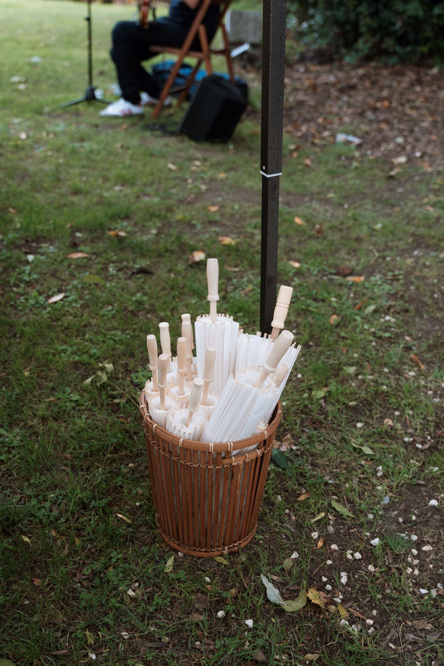 Decorative wooden basket filled with white paper parasols on grass.