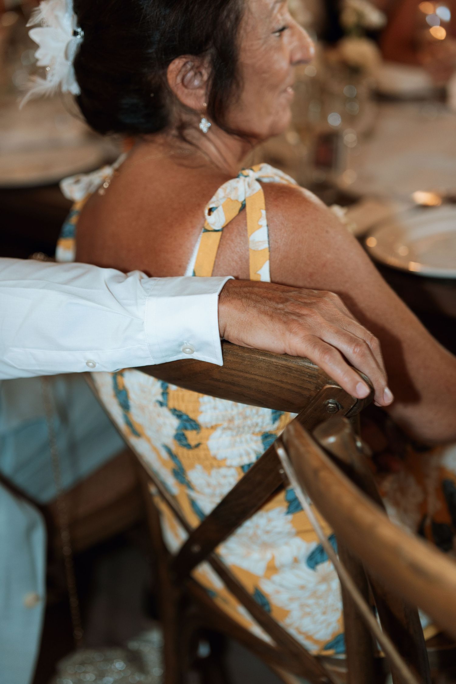 Close-up of guests seated in wooden chairs at a formal event.
