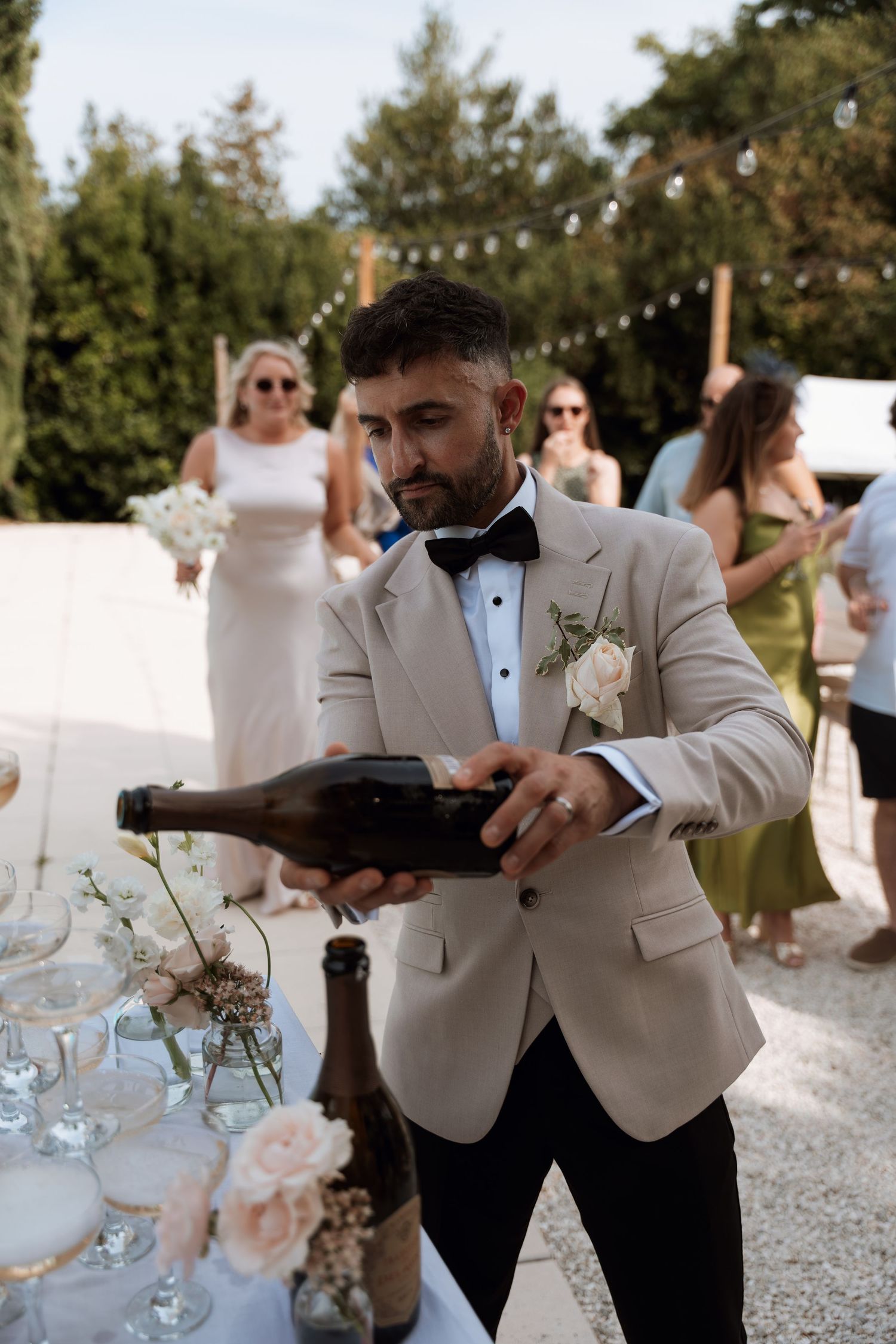 Wedding staff pouring champagne at an elegant outdoor reception.