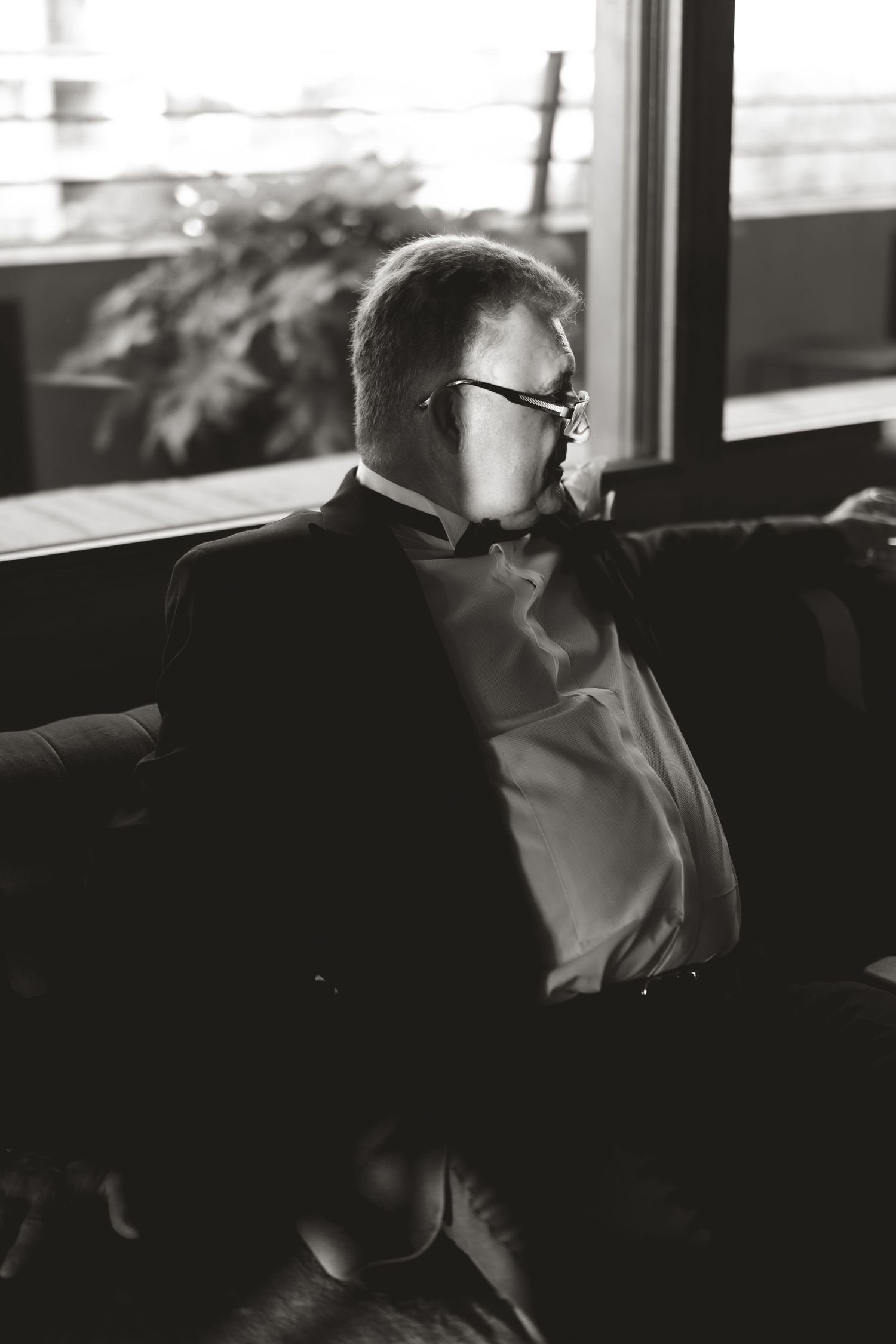 Black and white portrait of person in formal attire sitting in contemplative pose.