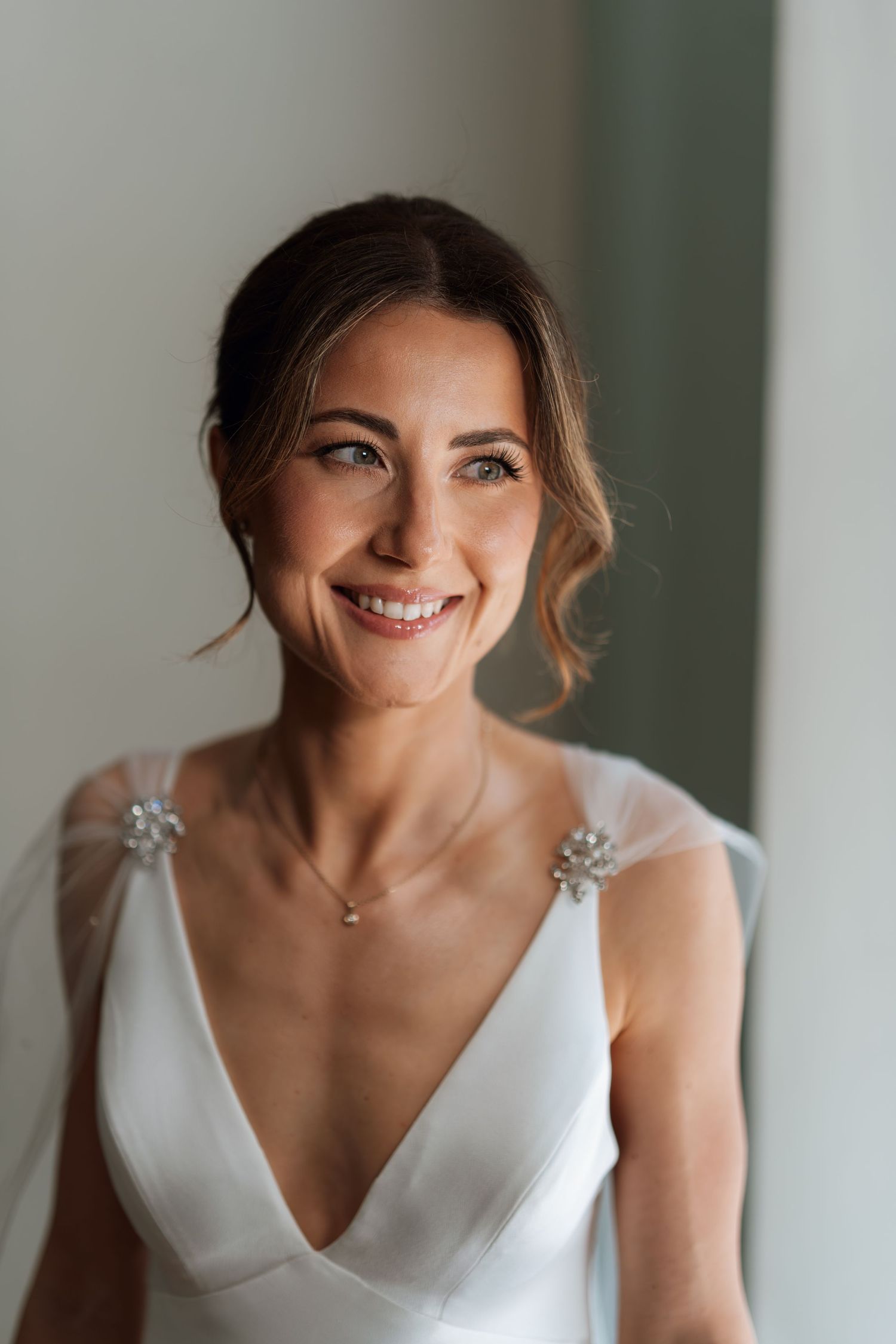 Bride smiling in an elegant white wedding dress with sparkly shoulder details.