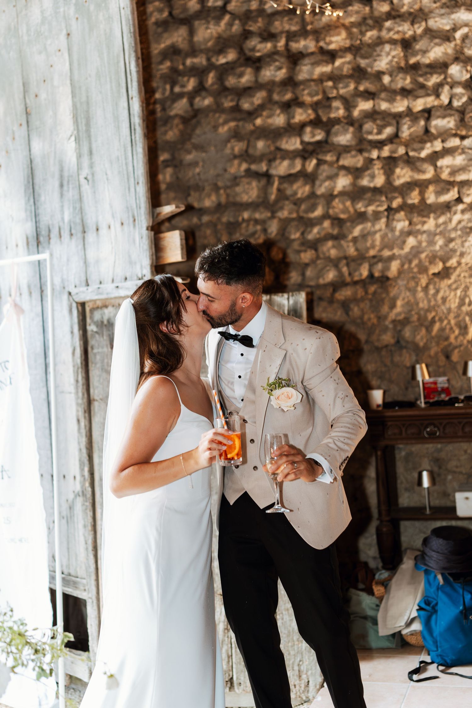 A couple shares drinks and laughter in a rustic stone-walled venue.