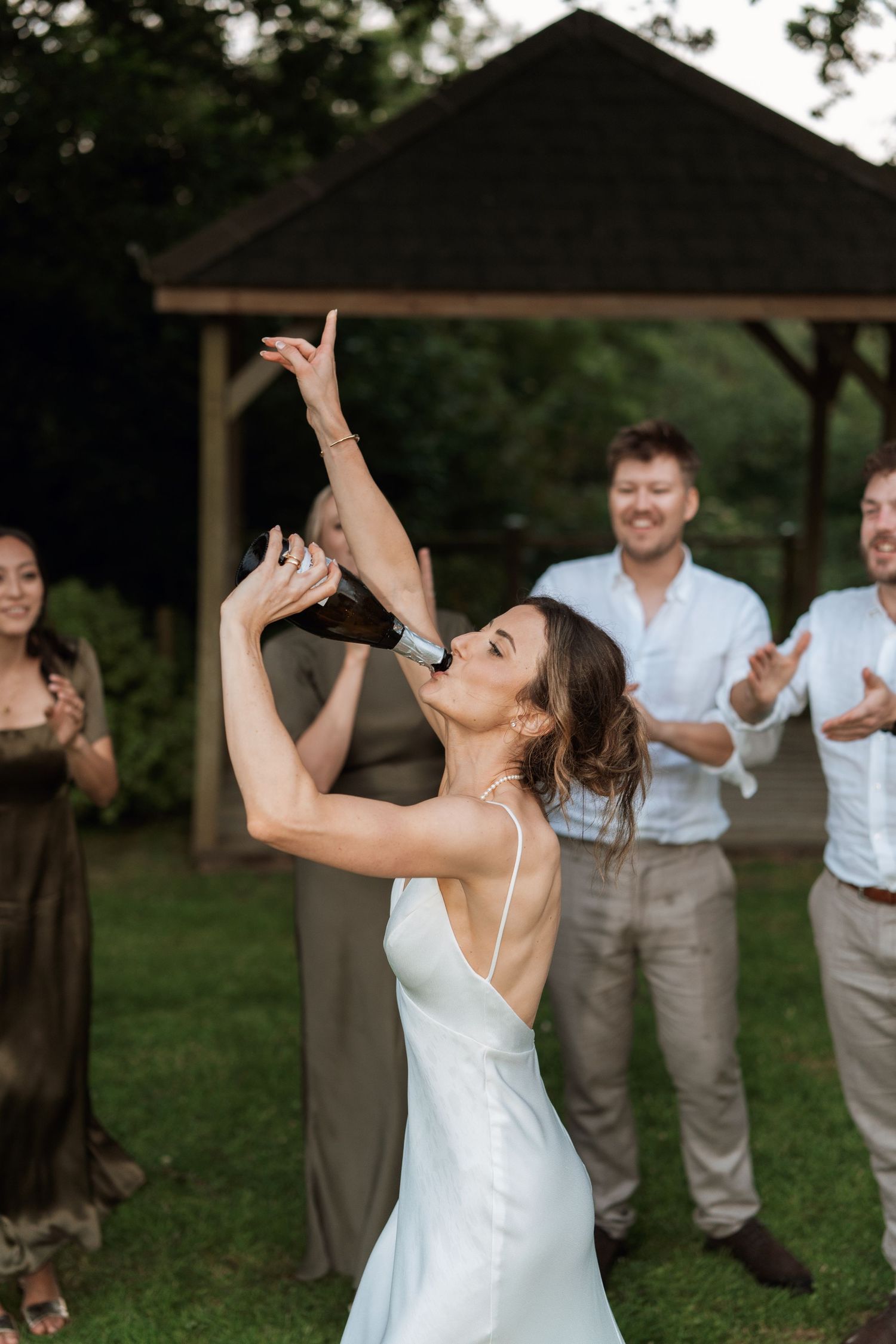 A joyful celebration moment at an outdoor wedding reception under a gazebo.
