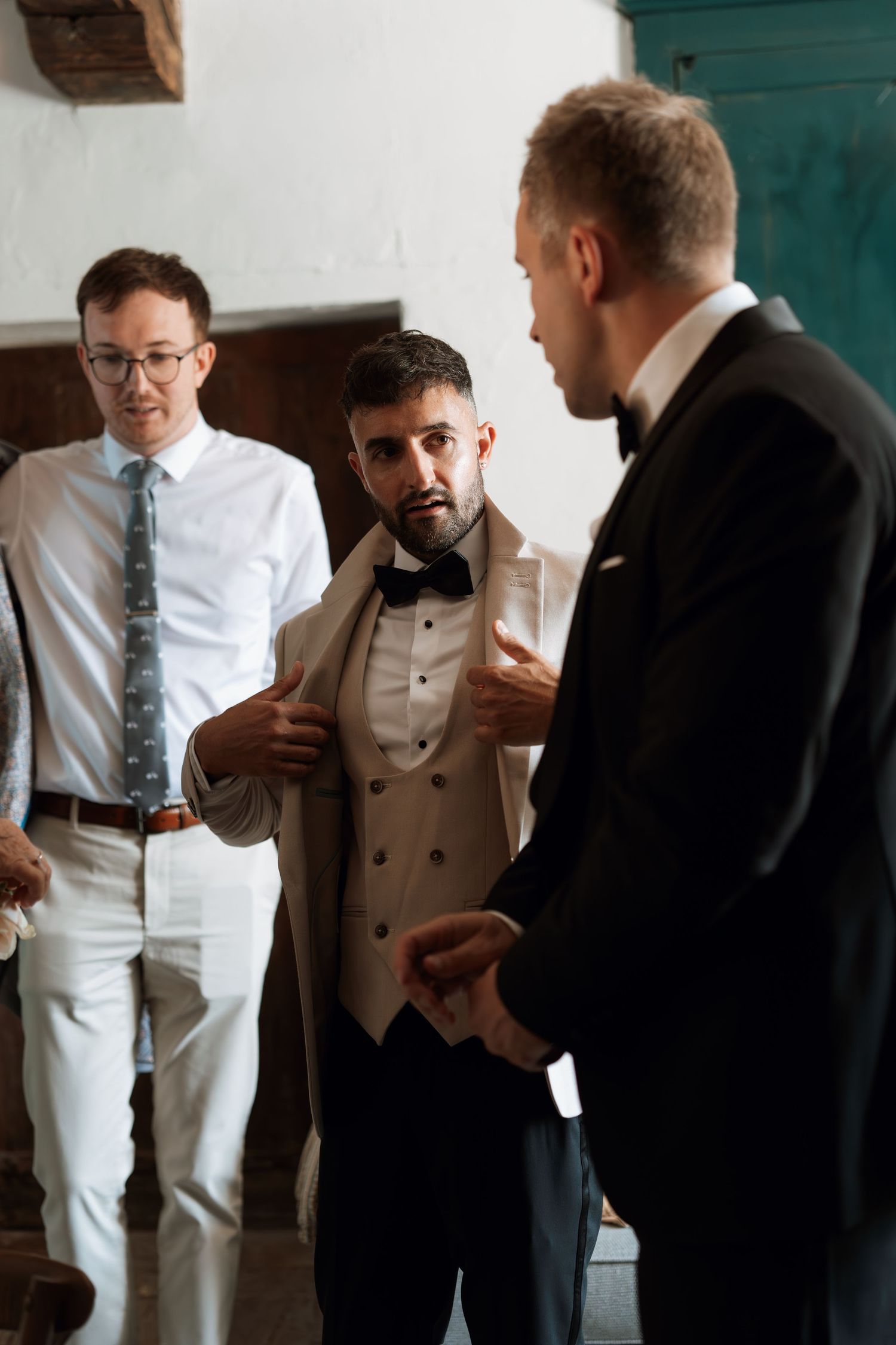 Wedding party members in formal attire gather and interact indoors.