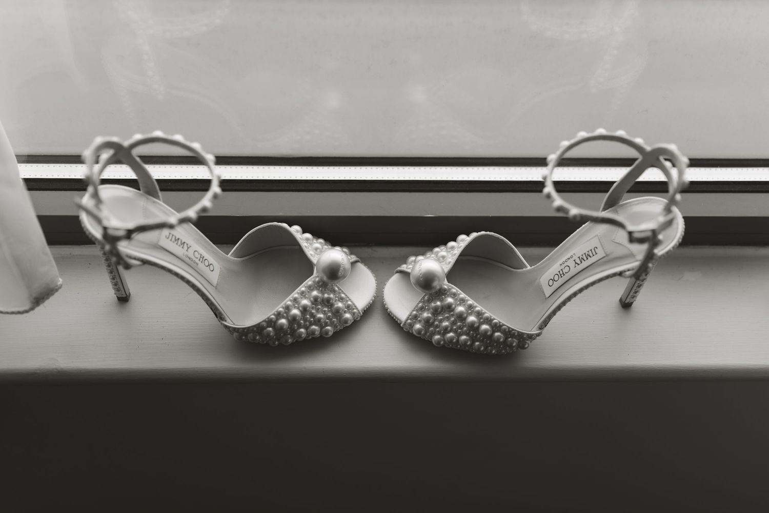 A series of white angel wing ornaments hanging from a curtain rod against a light background.