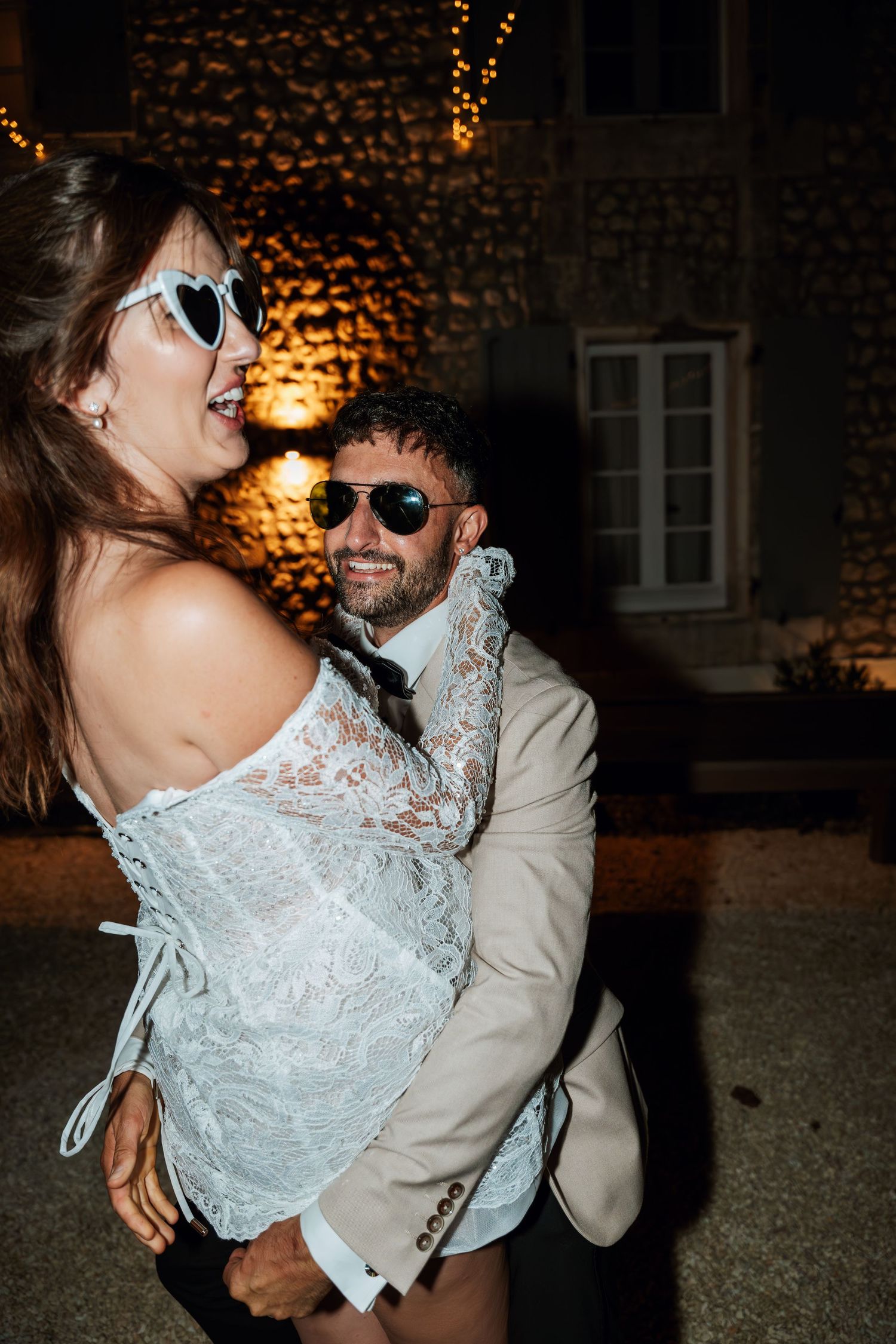 Couples dancing and embracing at an evening wedding reception with warm ambient lighting.