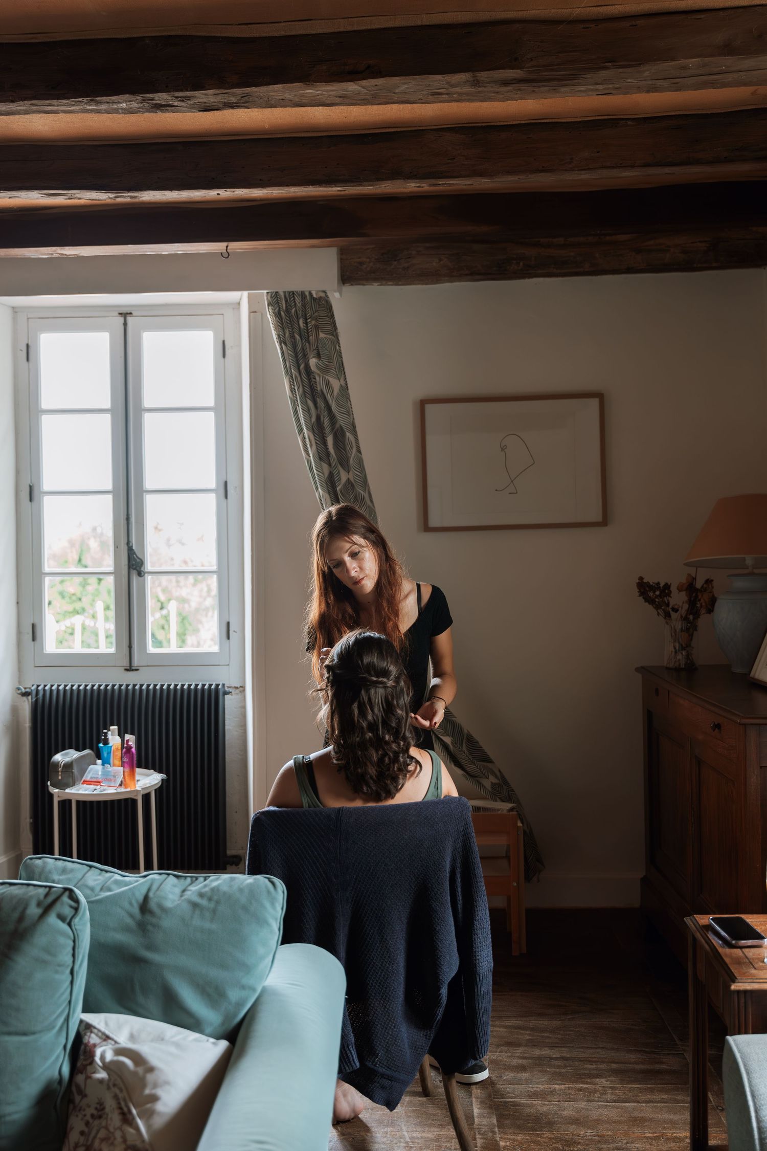 Interior scene showing a teal couch against dark wood beams in a rustic room with natural lighting.