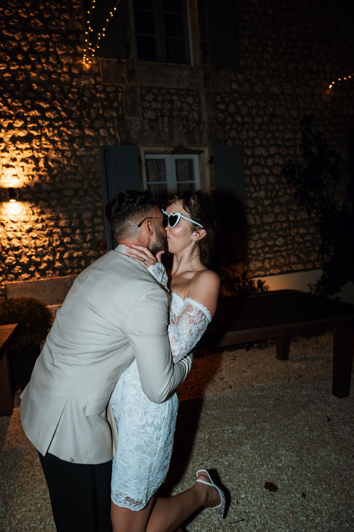 Romantic evening dance moment against illuminated stone building facade.