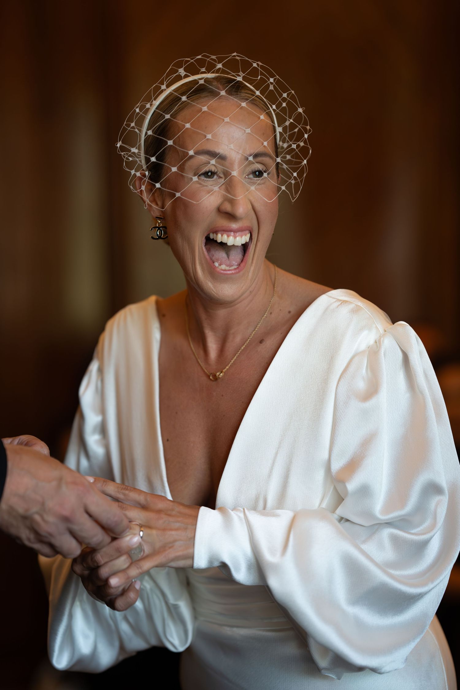 A joyful moment captured in white bridal attire with a vintage-style birdcage veil.