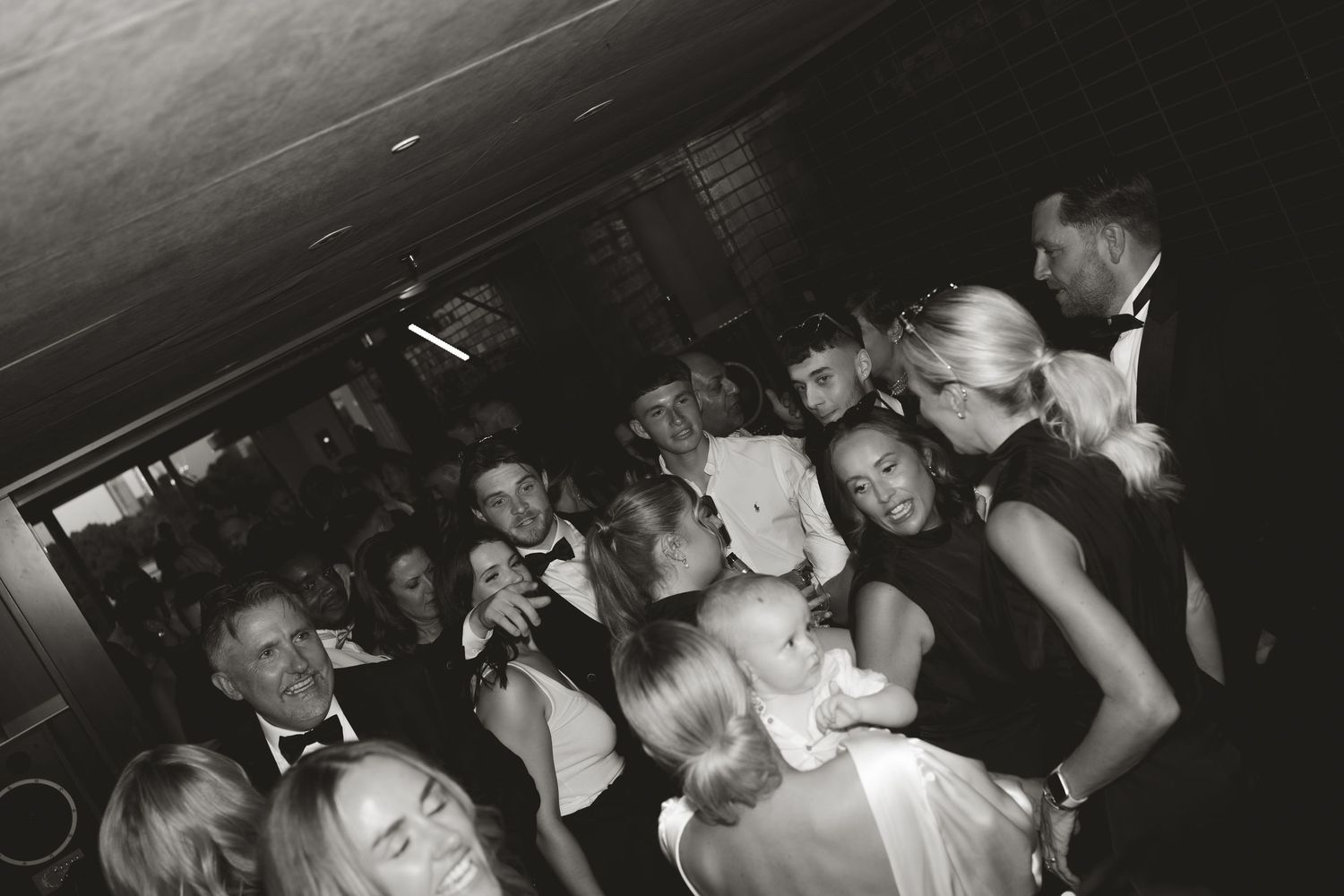 Black and white photo of a crowded wedding reception dance floor.