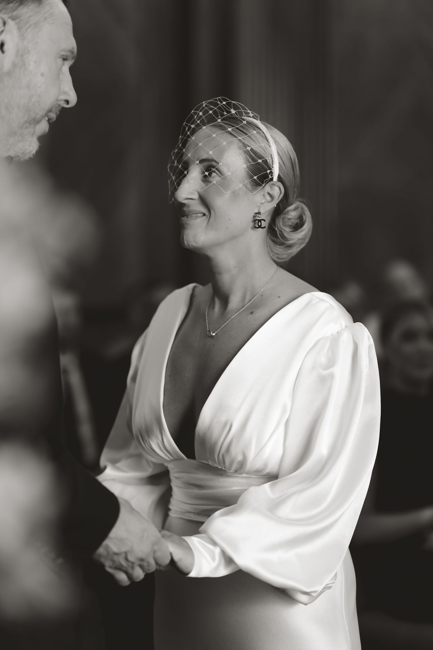 Black and white portrait of someone in white dress with vintage-inspired hair and jewelry.