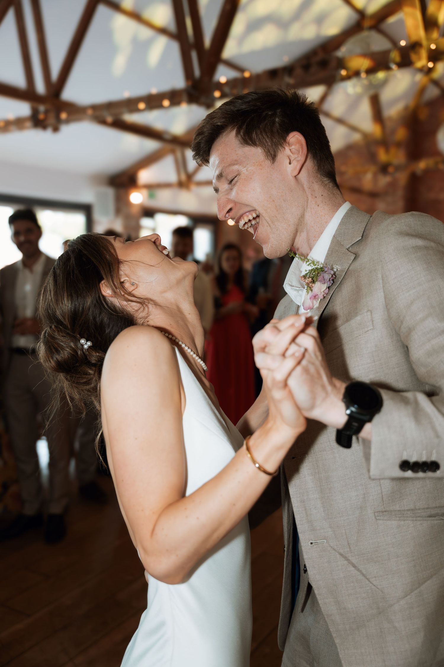 Couple sharing intimate dance moves under rustic wooden beams with twinkle lights.