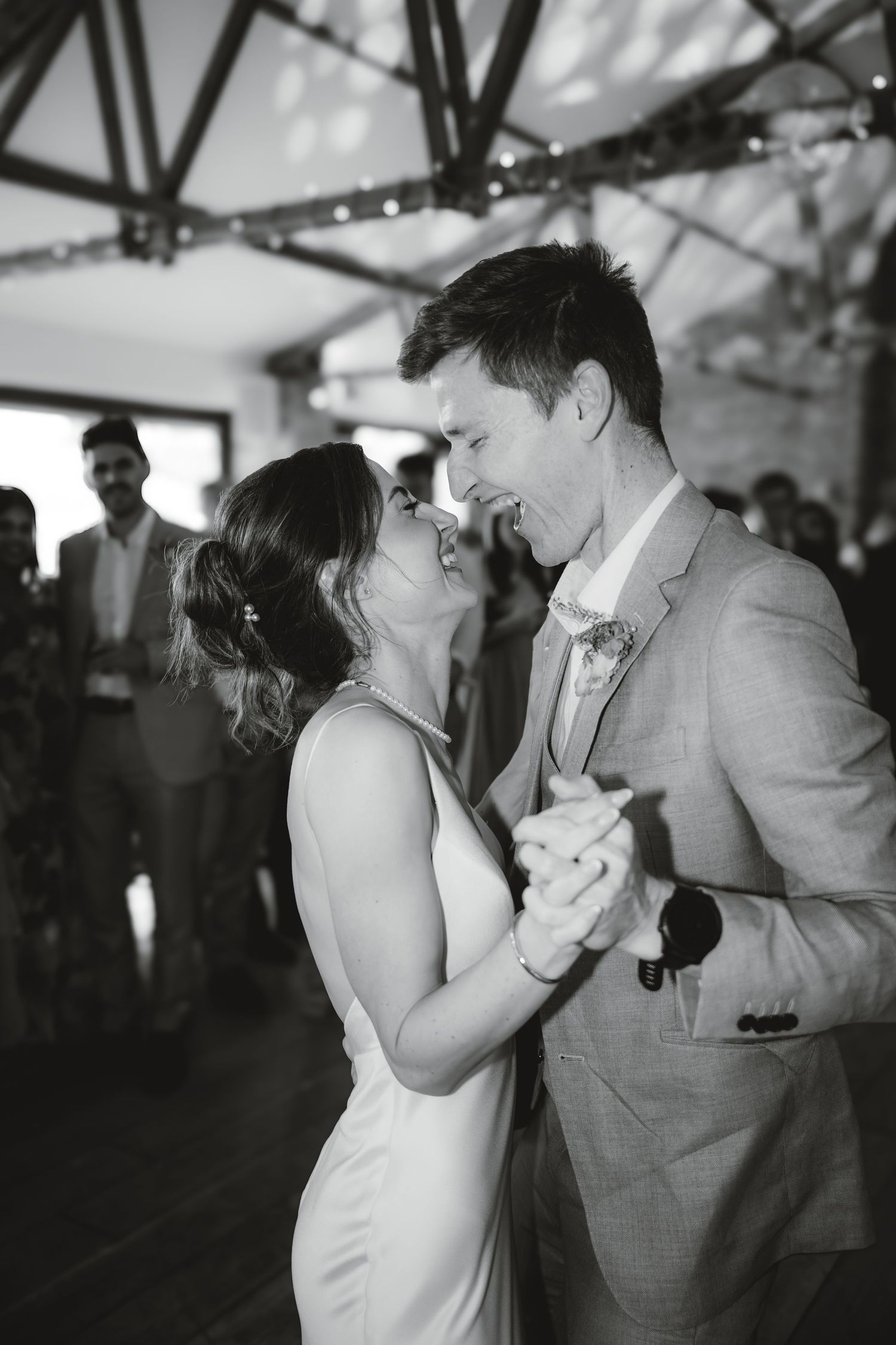 A black and white photo captures an intimate first dance moment at a wedding reception.