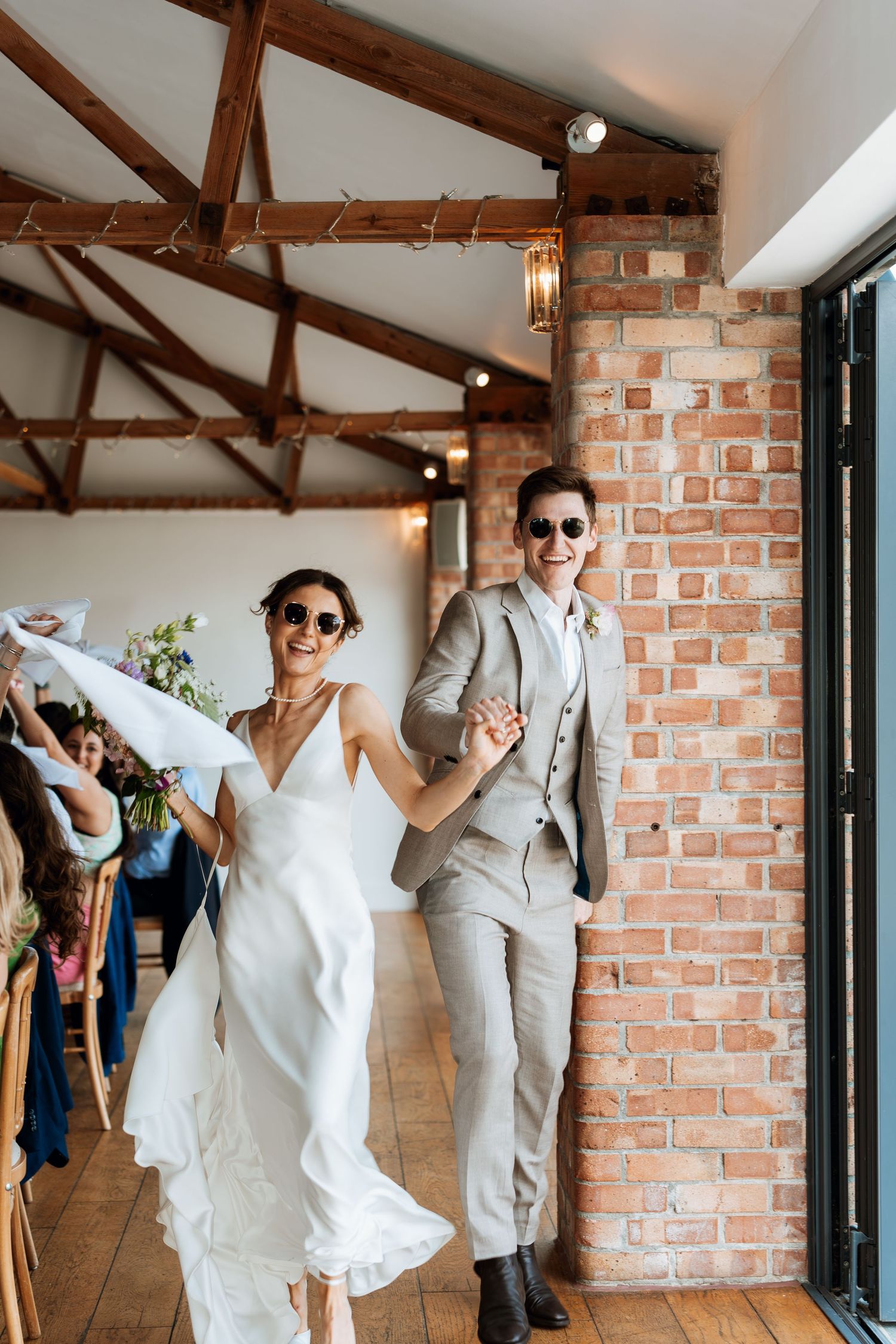 Joyful celebration inside a rustic brick-walled venue with exposed wooden beams.