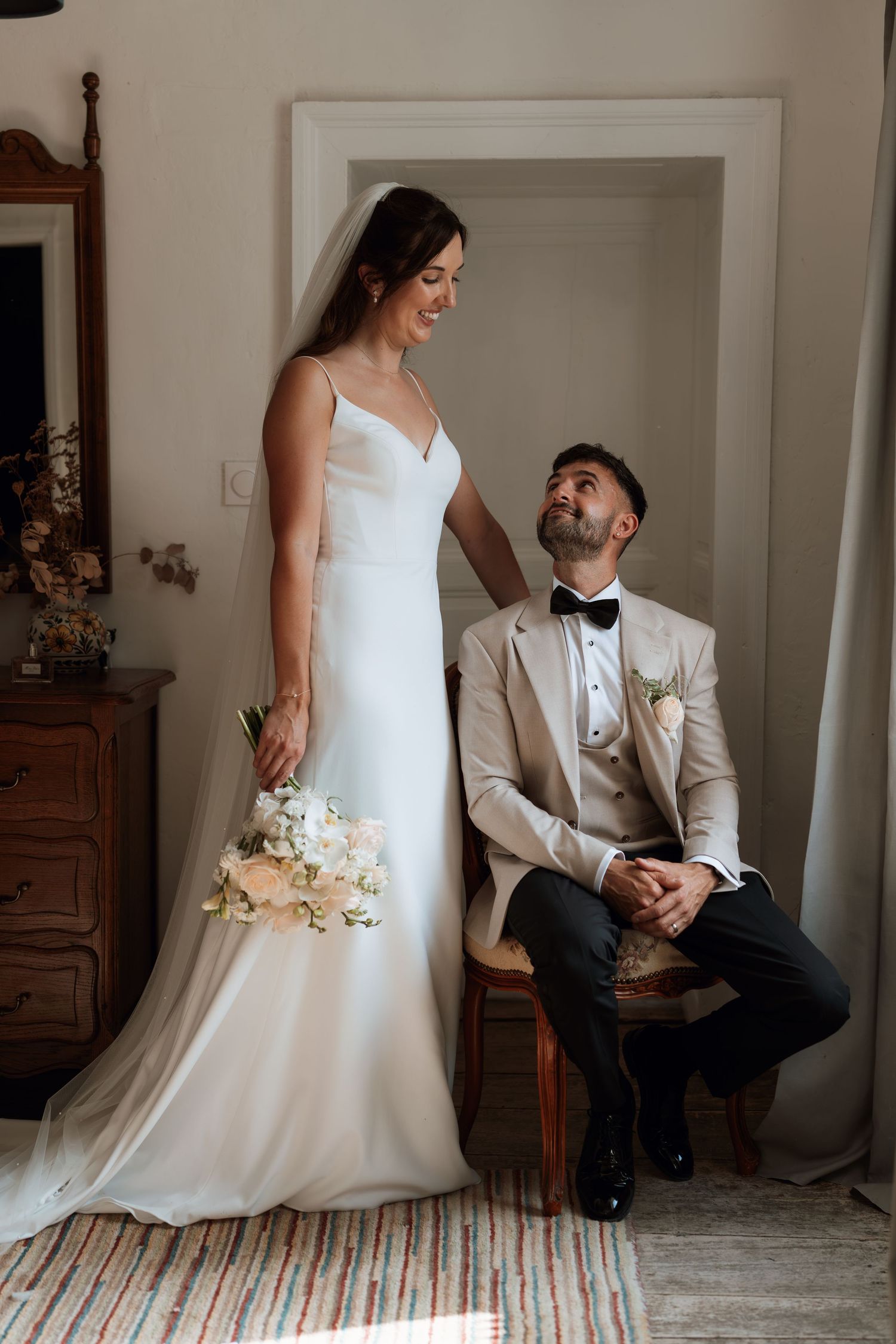Intimate wedding portrait session with couple in white dress and beige suit indoors.