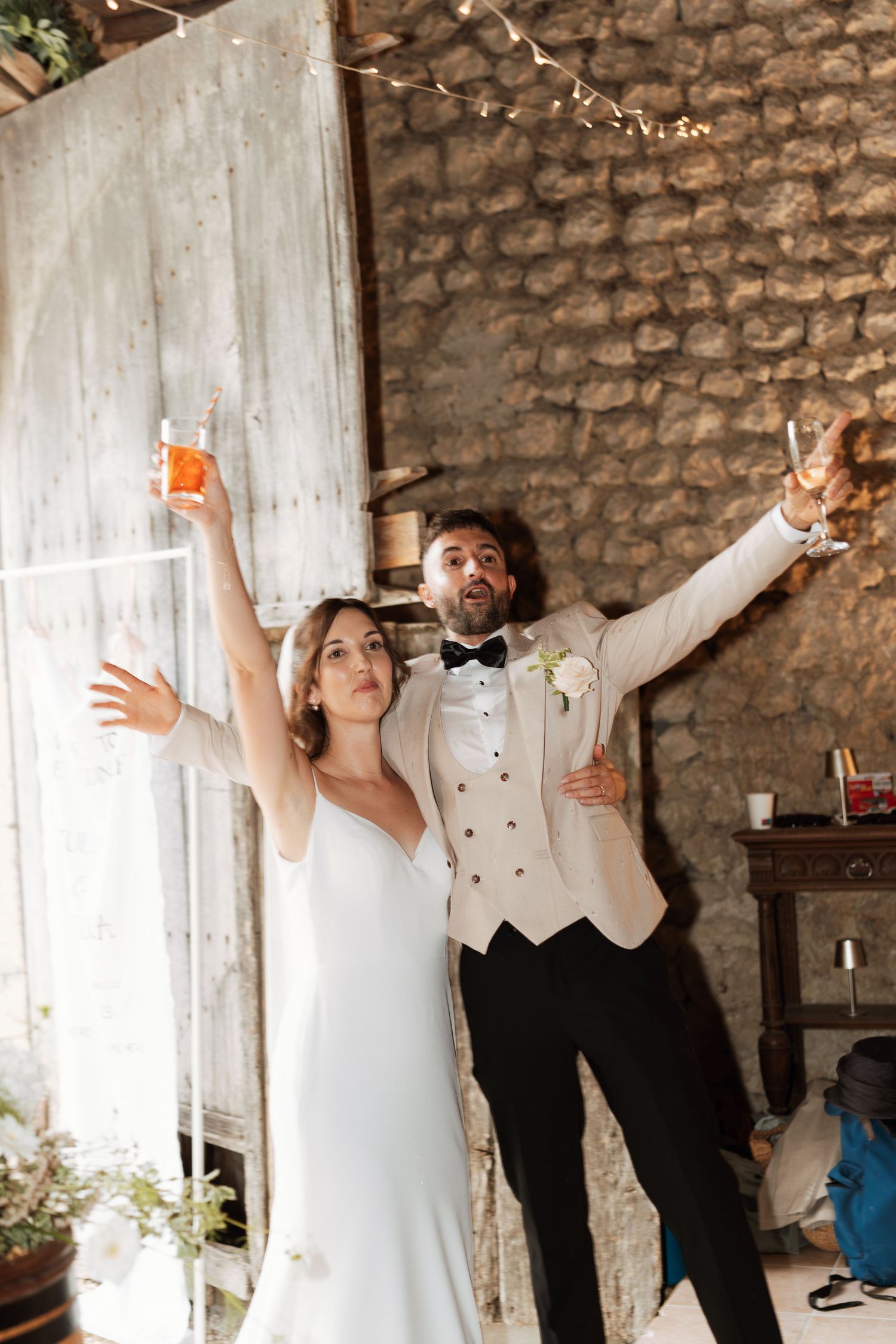 Celebratory moment with drinks in a rustic stone venue with string lights.