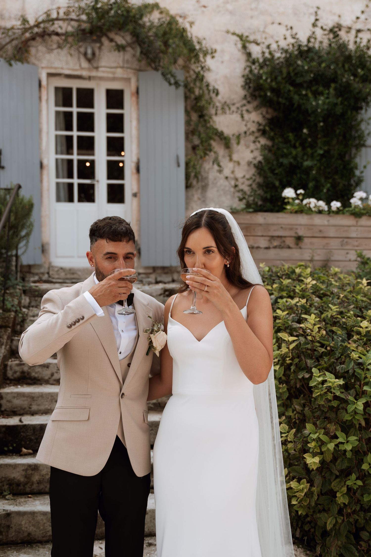 Wedding couple sharing an emotional moment in front of a stone building with climbing vines.