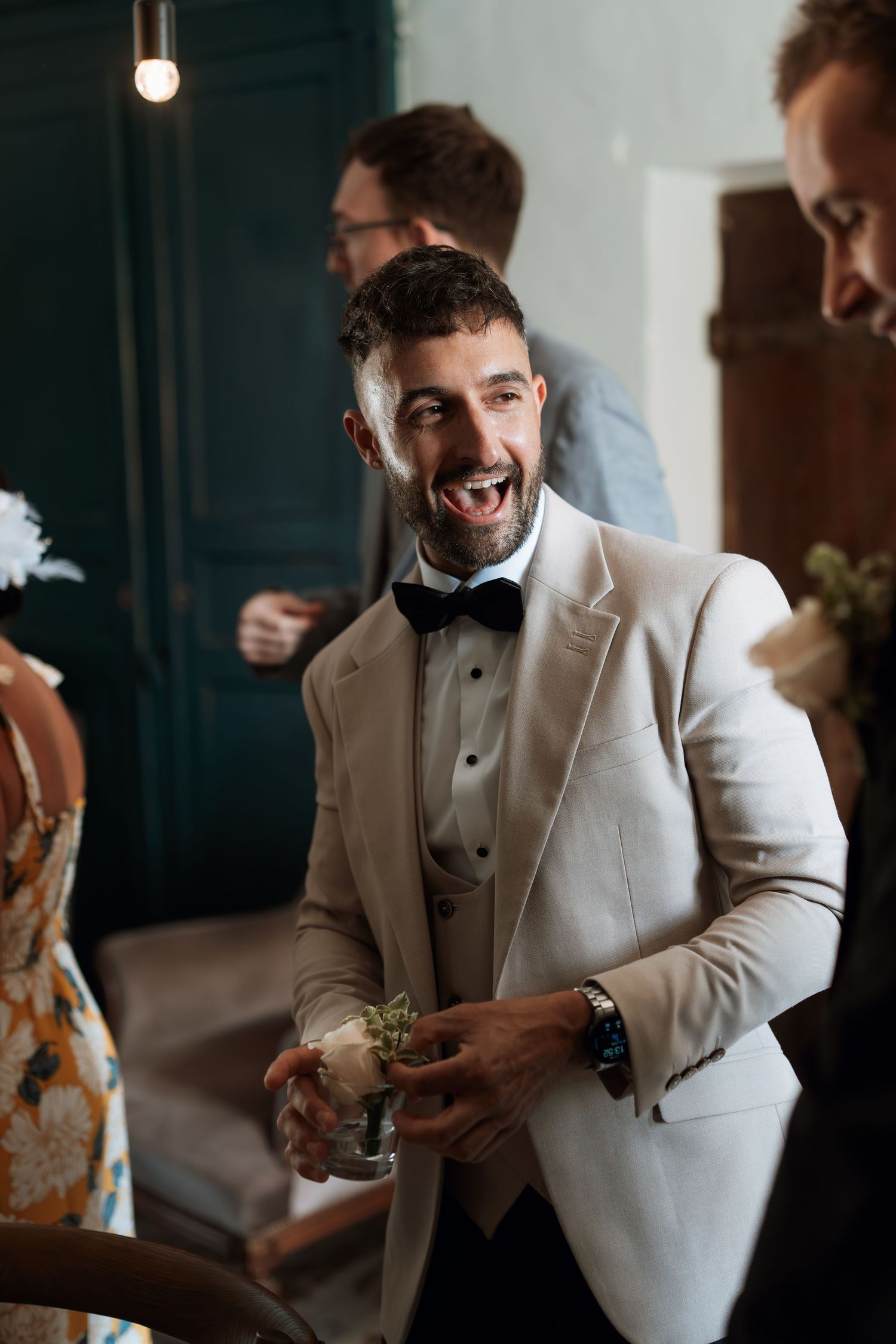Person in white tuxedo jacket and bow tie enjoying a celebratory moment indoors.