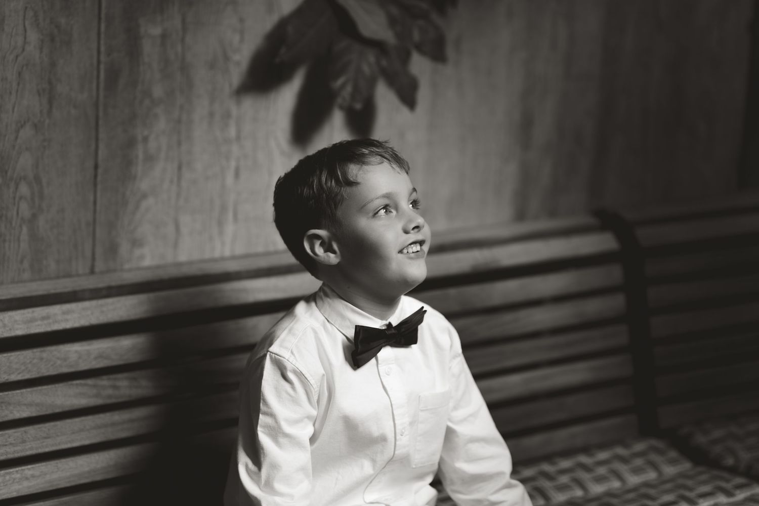 Black and white portrait of a young child smiling and looking upward.