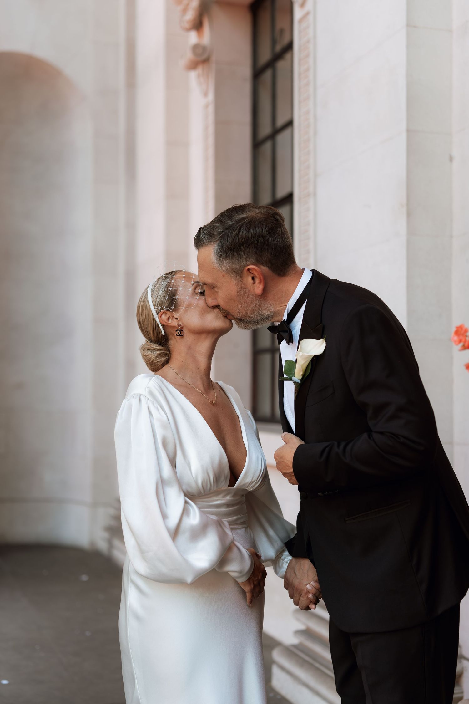 Romantic moment between newlyweds in front of white columned architecture.