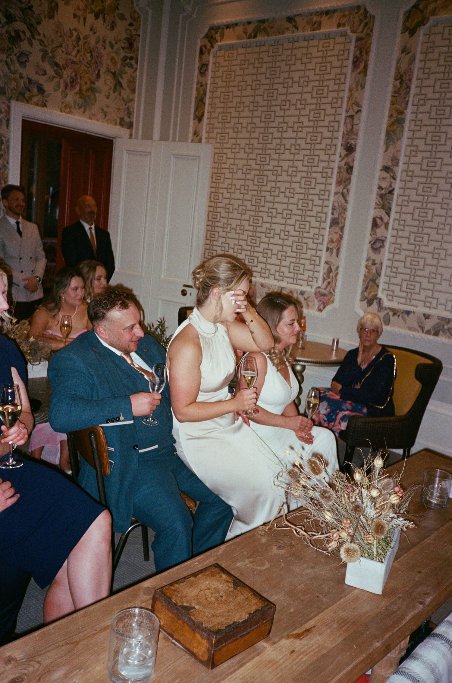 Four sequential photos show guests celebrating and interacting at a wedding reception with rustic wooden tables and decor.