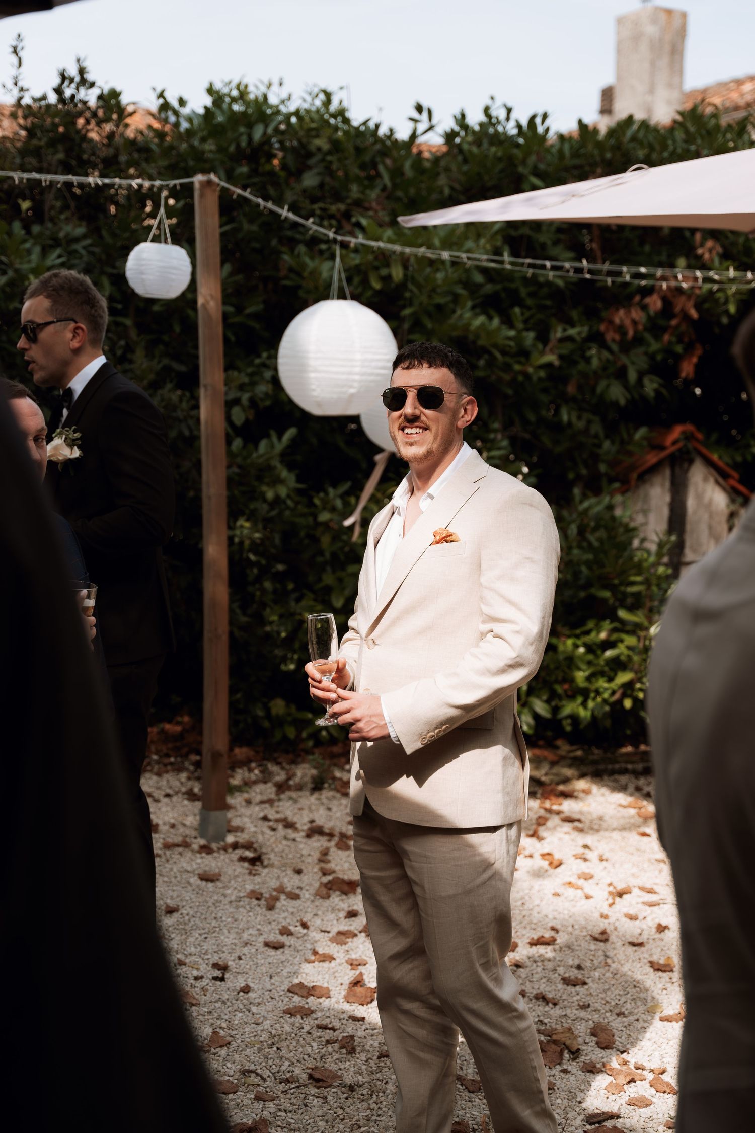 Wedding guests in formal attire enjoying an outdoor celebration with white paper lanterns.