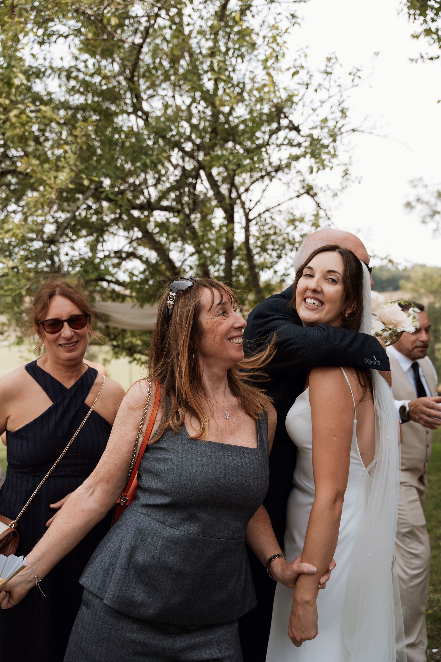 Wedding guests laugh and dance together at an outdoor celebration.