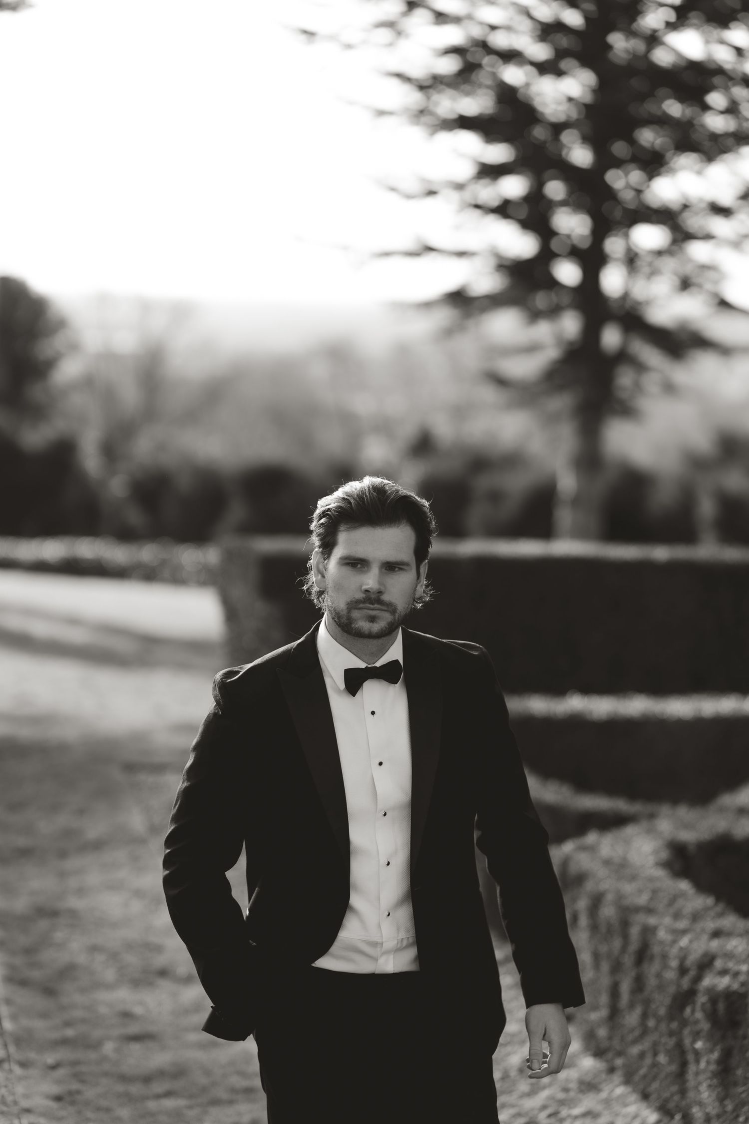 Black and white photo of someone in a tuxedo running through an outdoor field.