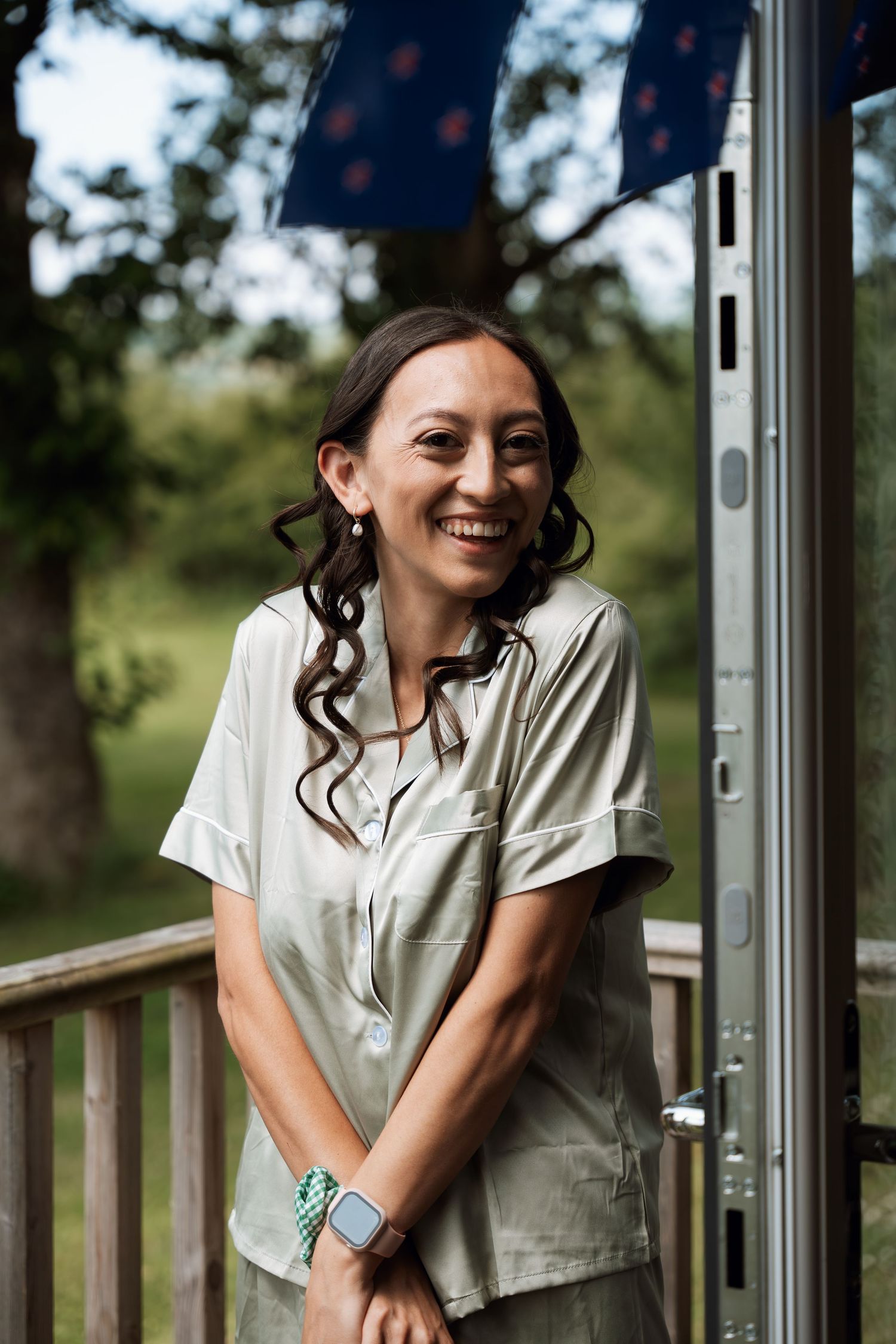 Person in white button-down shirt leans against wooden railing outdoors.