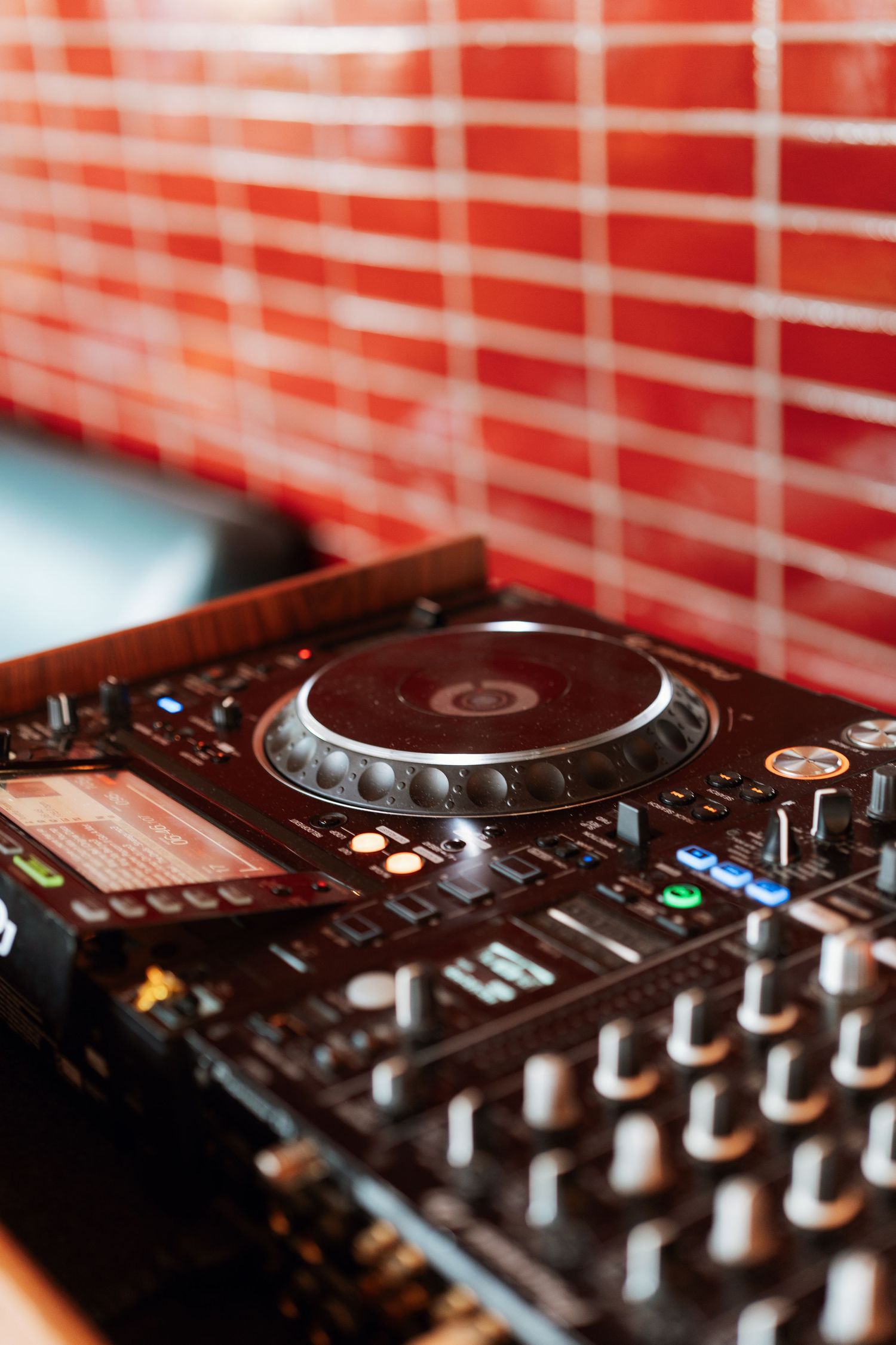 Close-up of professional DJ equipment with red lighting and control knobs.