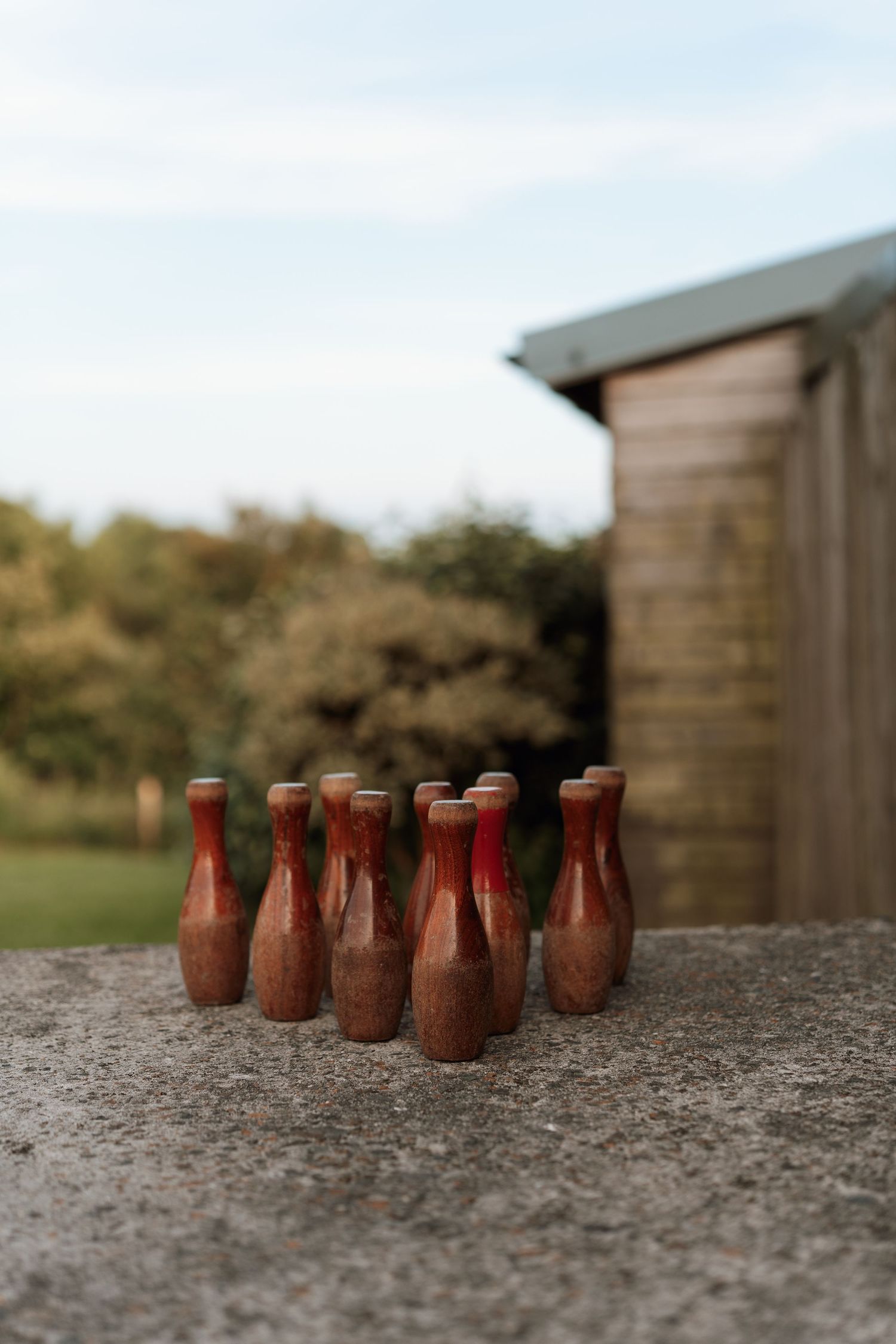 Small red bowling pins arranged in rows on a textured concrete surface.