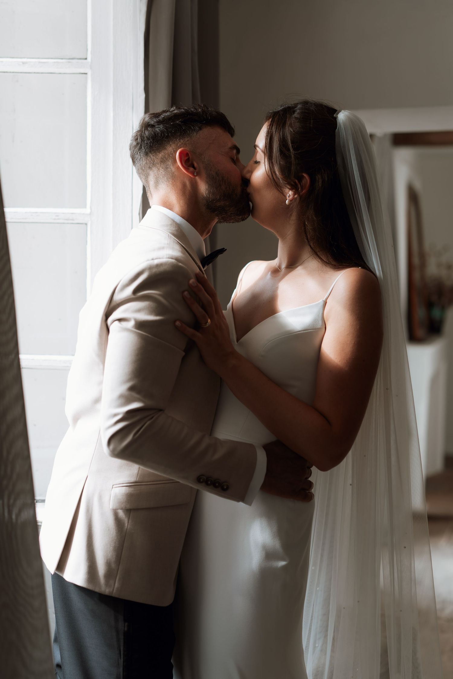 A romantic silhouette of a couple sharing an intimate moment near a window.