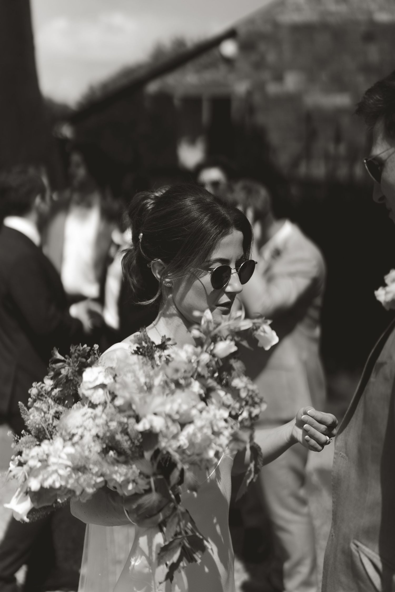 Wedding party members in sunglasses holding elegant white and pink bouquets.