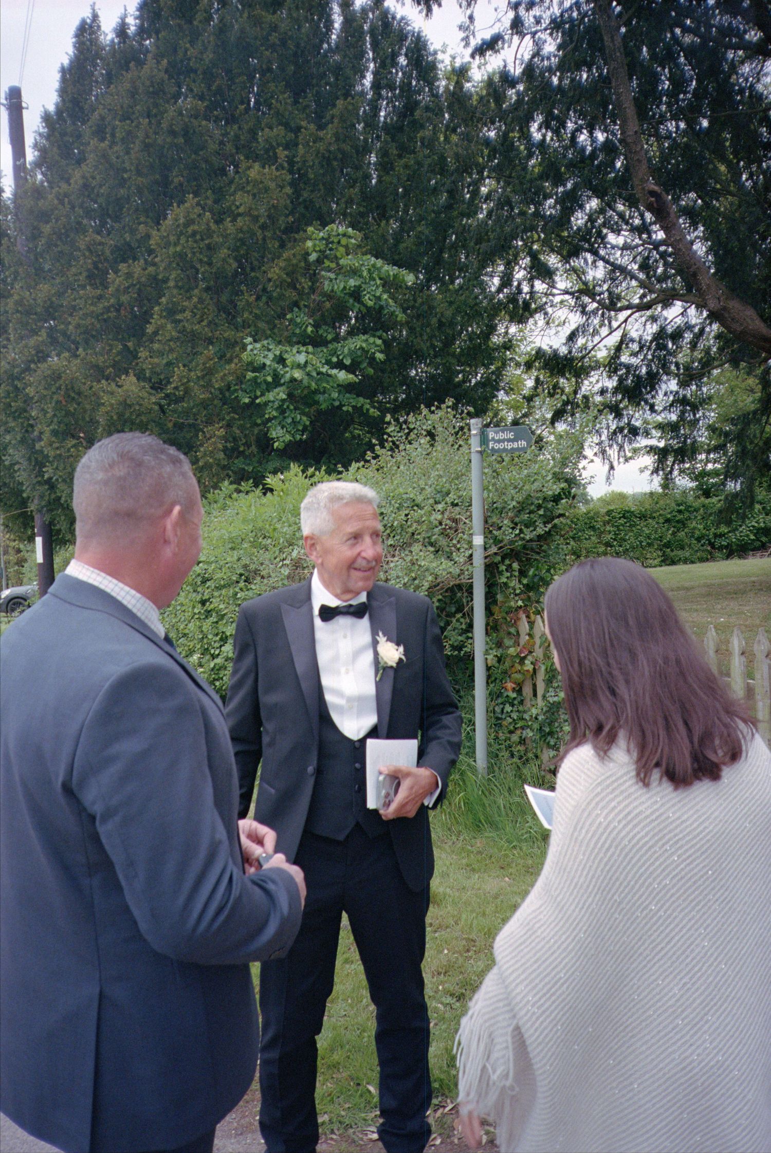 A sequence of photos showing people in formal attire having a conversation outdoors near trees and greenery.