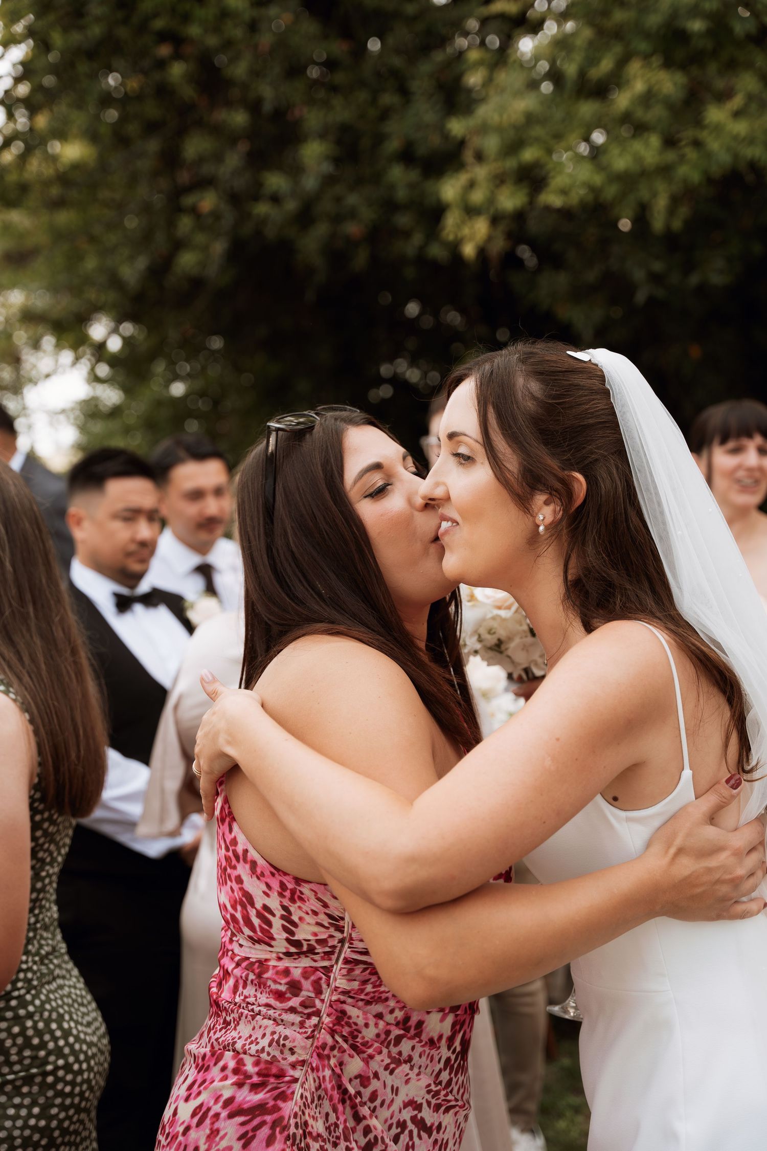 A sequence of candid moments at an outdoor wedding celebration showing embraces between guests and the bride.