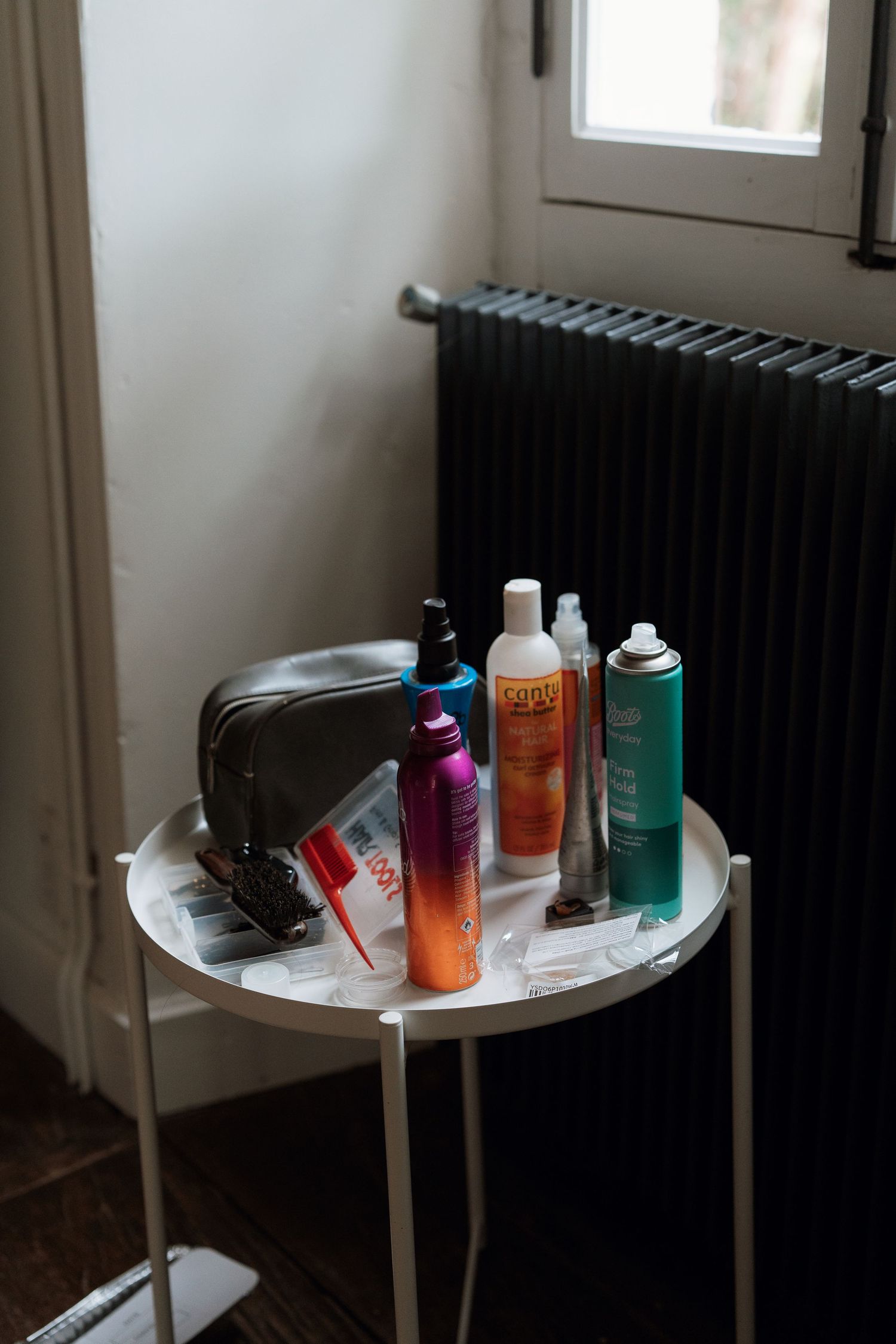 Various personal care and styling products arranged on a small white side table against a dark background.