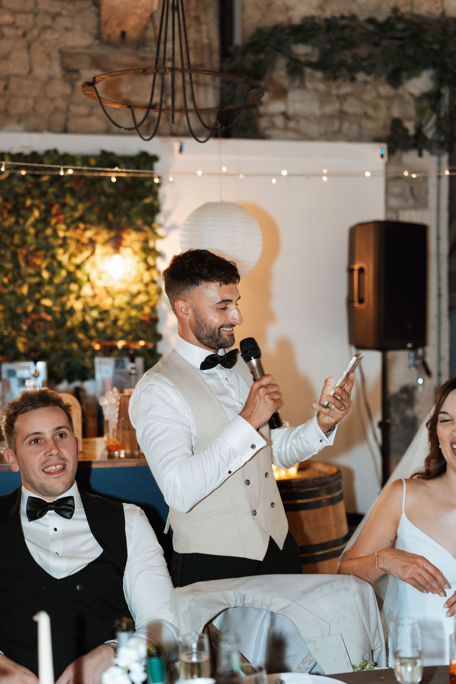 Men in white tuxedos and bow ties laughing during a formal event.